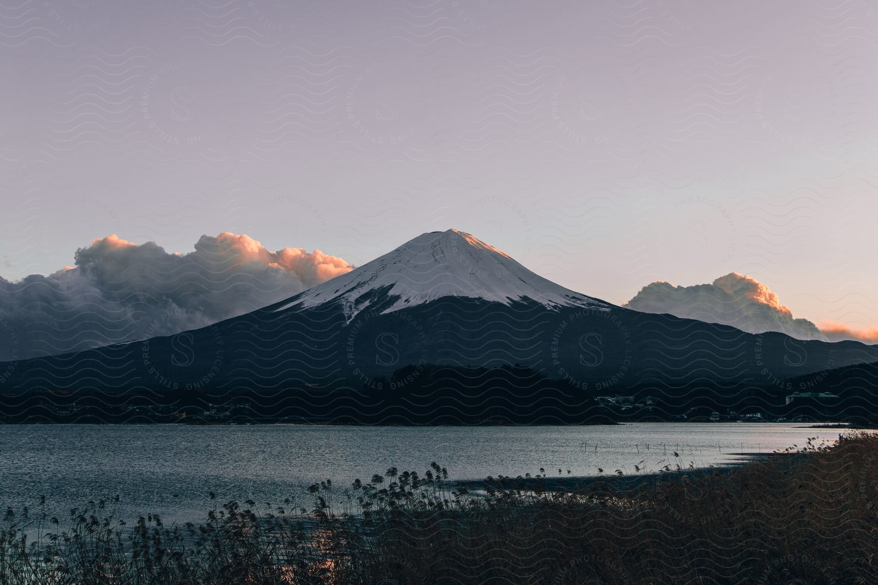 A snowcovered mountain behind a lake at dusk in japan