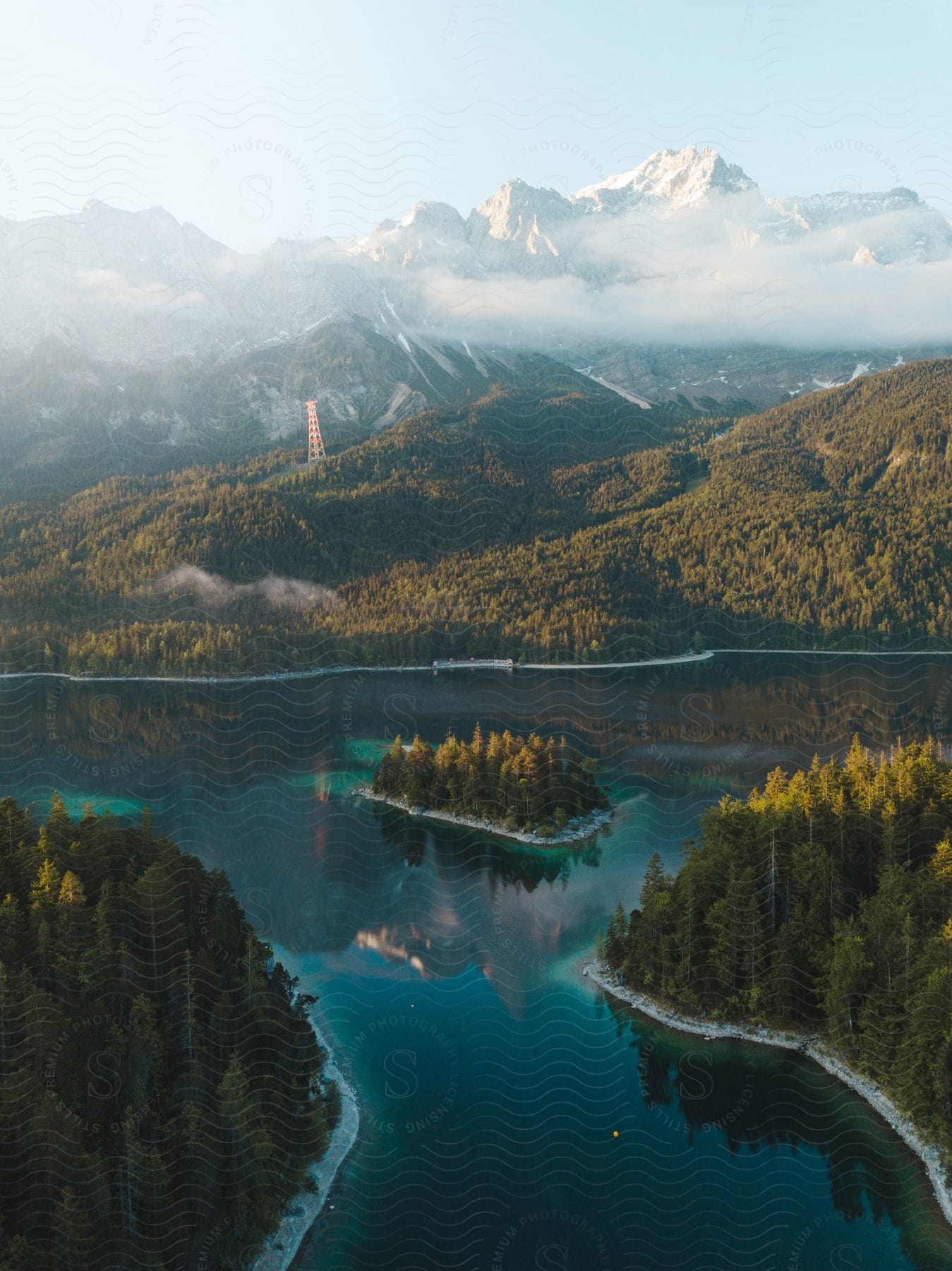 A river splits in the forest downhill from snowy mountains in the mist