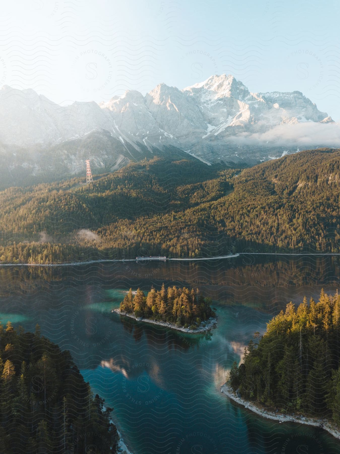 A turquoise lake with a treecovered island is surrounded by forests and mountains