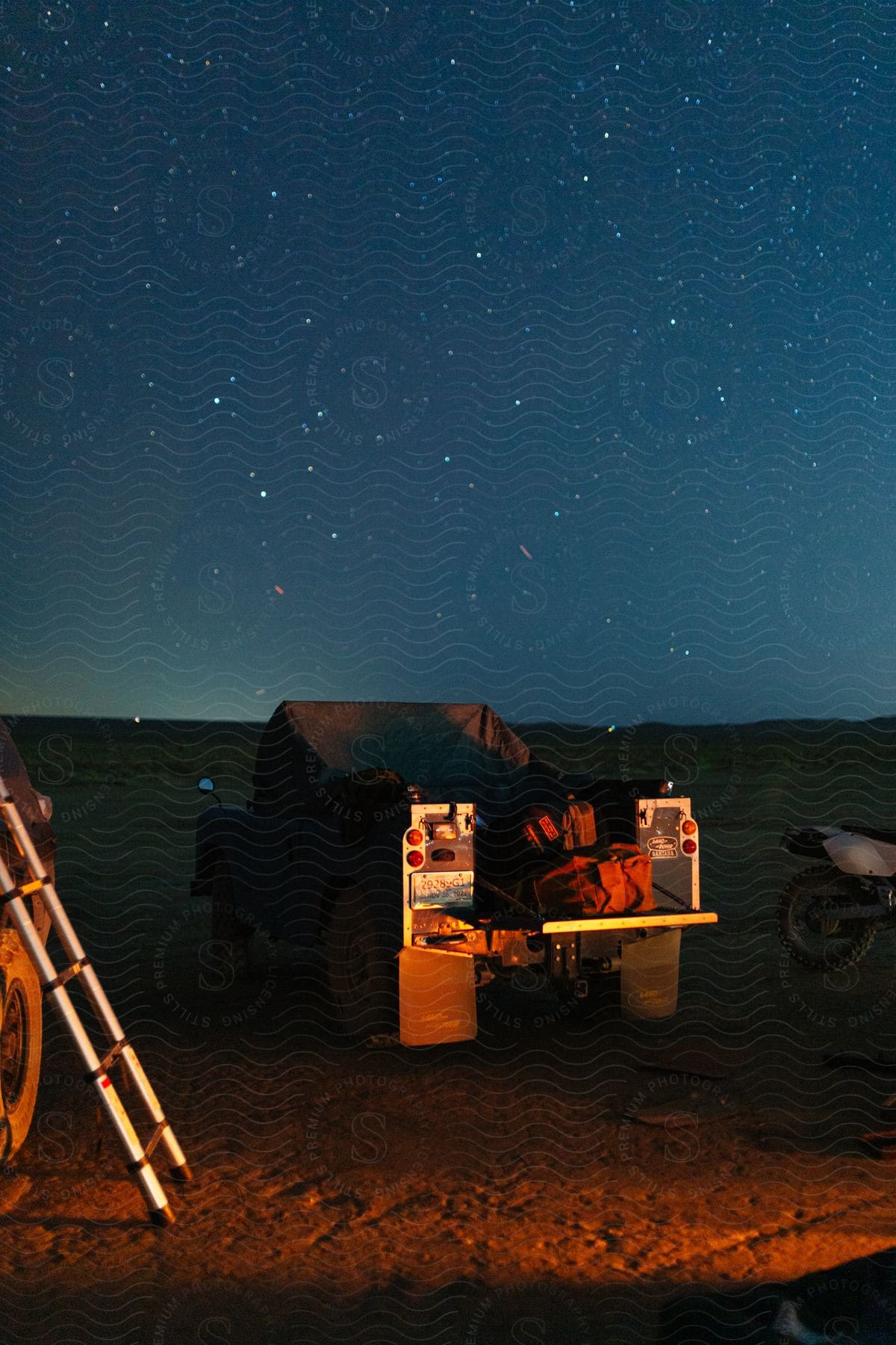 An all terrain vehicle in the desert with cargo in the back under a starry sky