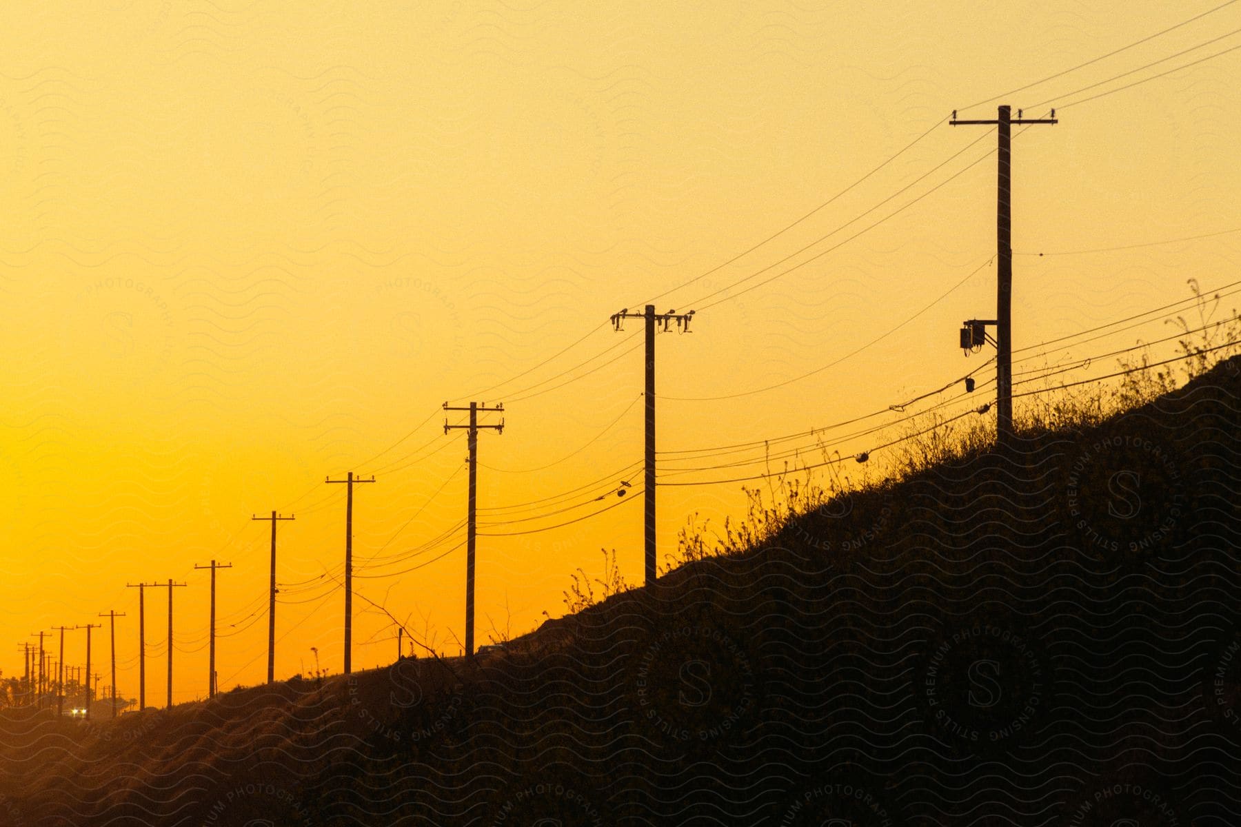 Power line silhouette under a bright orangish yellow sky