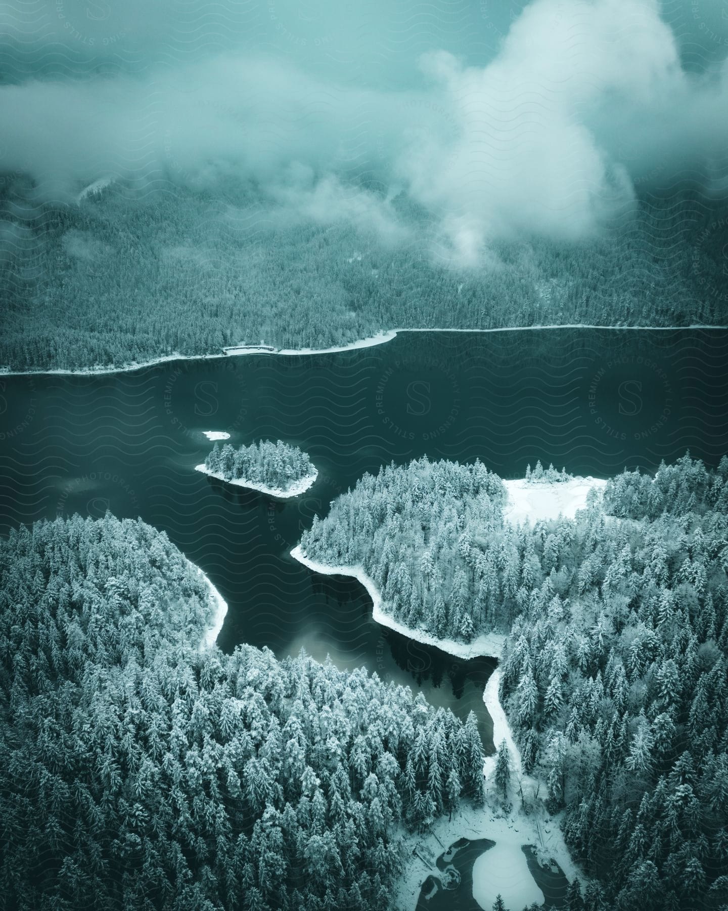 Snow covered forest pine and lake under cloud cover at night in an aerial perspective