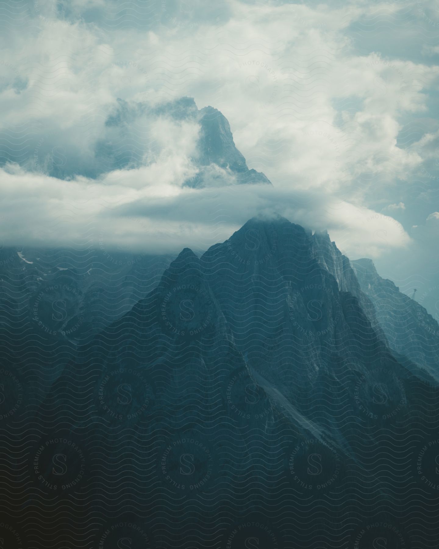 Tall pointy mountain ridges with fog and clouds settled over the mountain range during the day