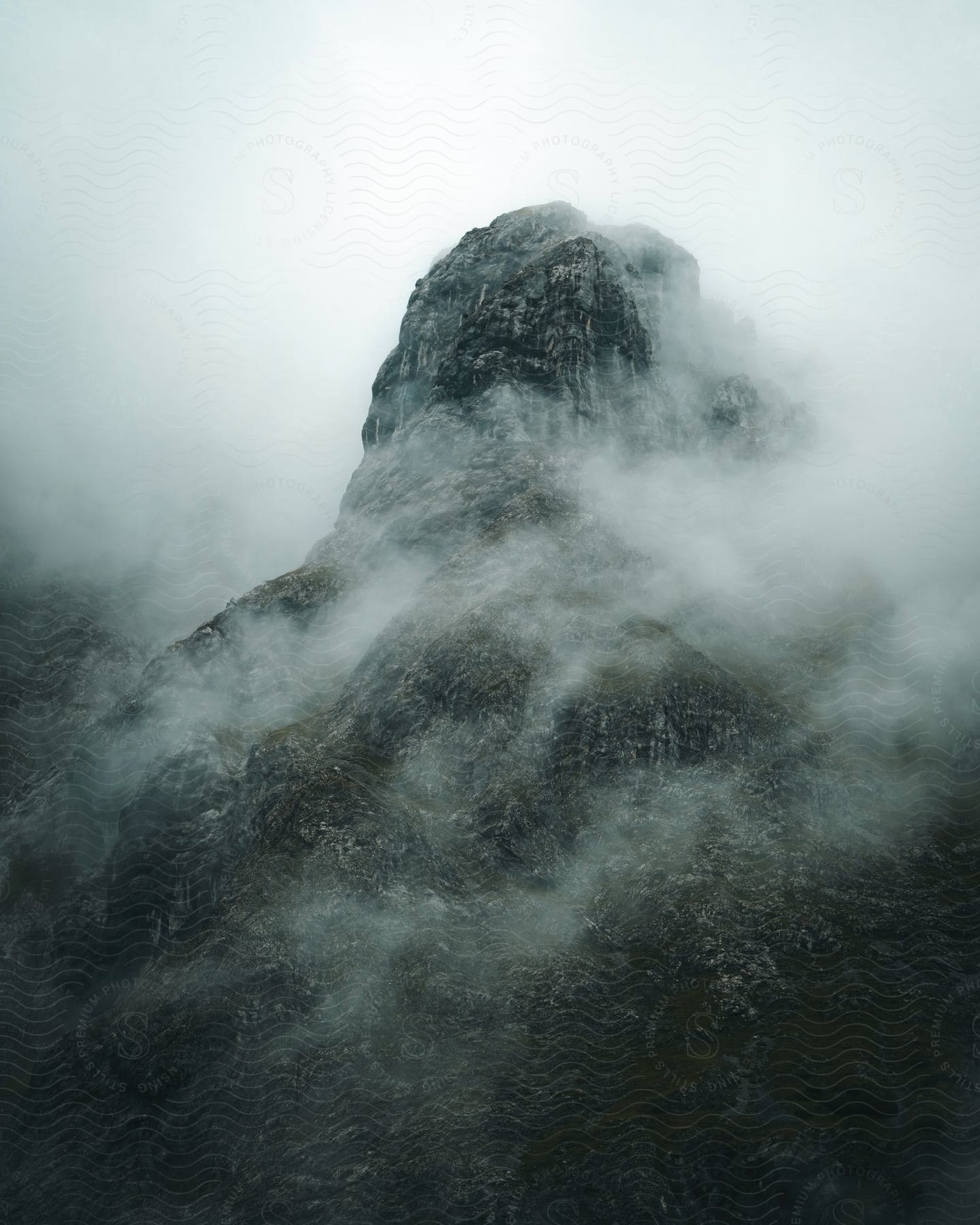 A mountain is shrouded in fog and clouds on an overcast day