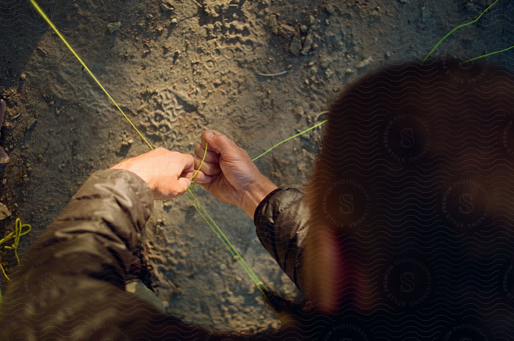 A Man Wearing A Cold Coat Is Seen Tying A Yellow Thread