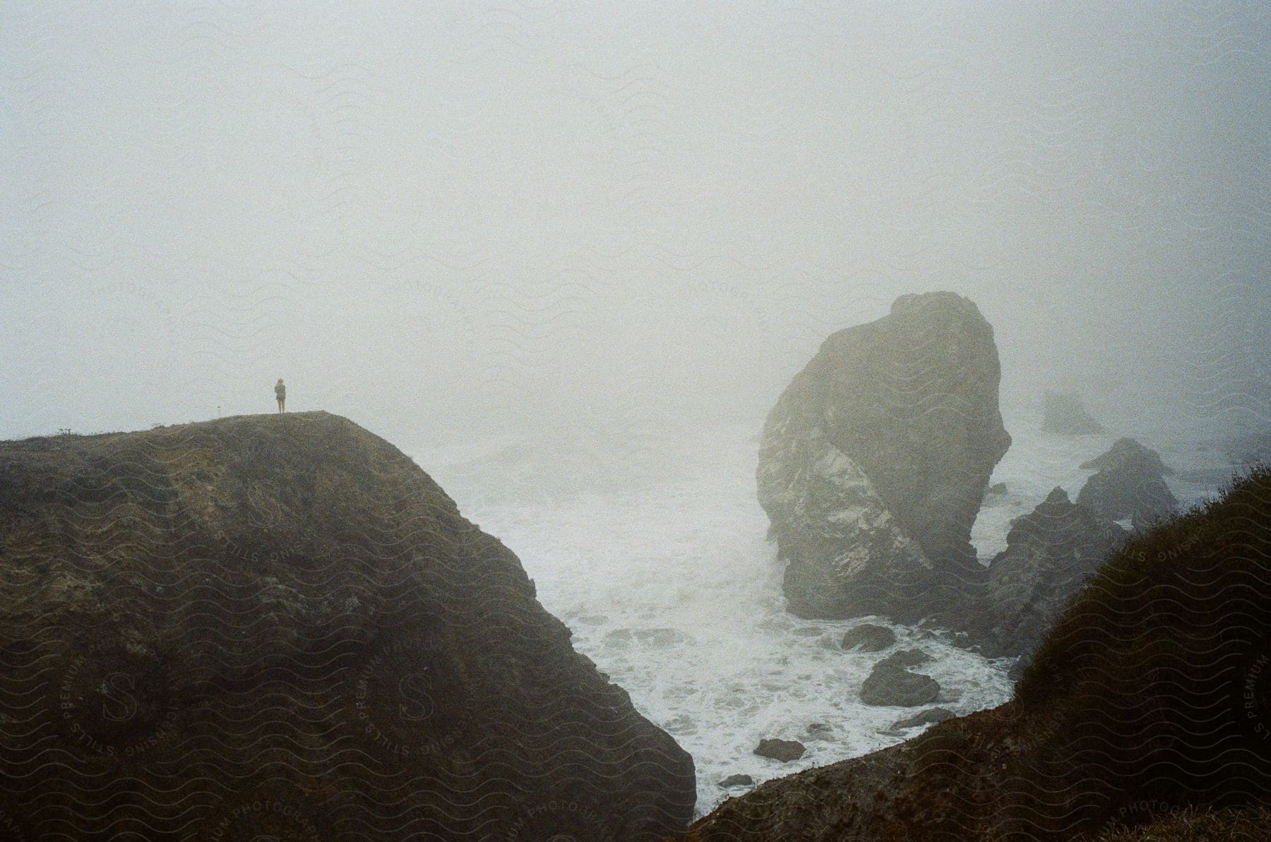 A person standing at the edge of a cliff on the sea