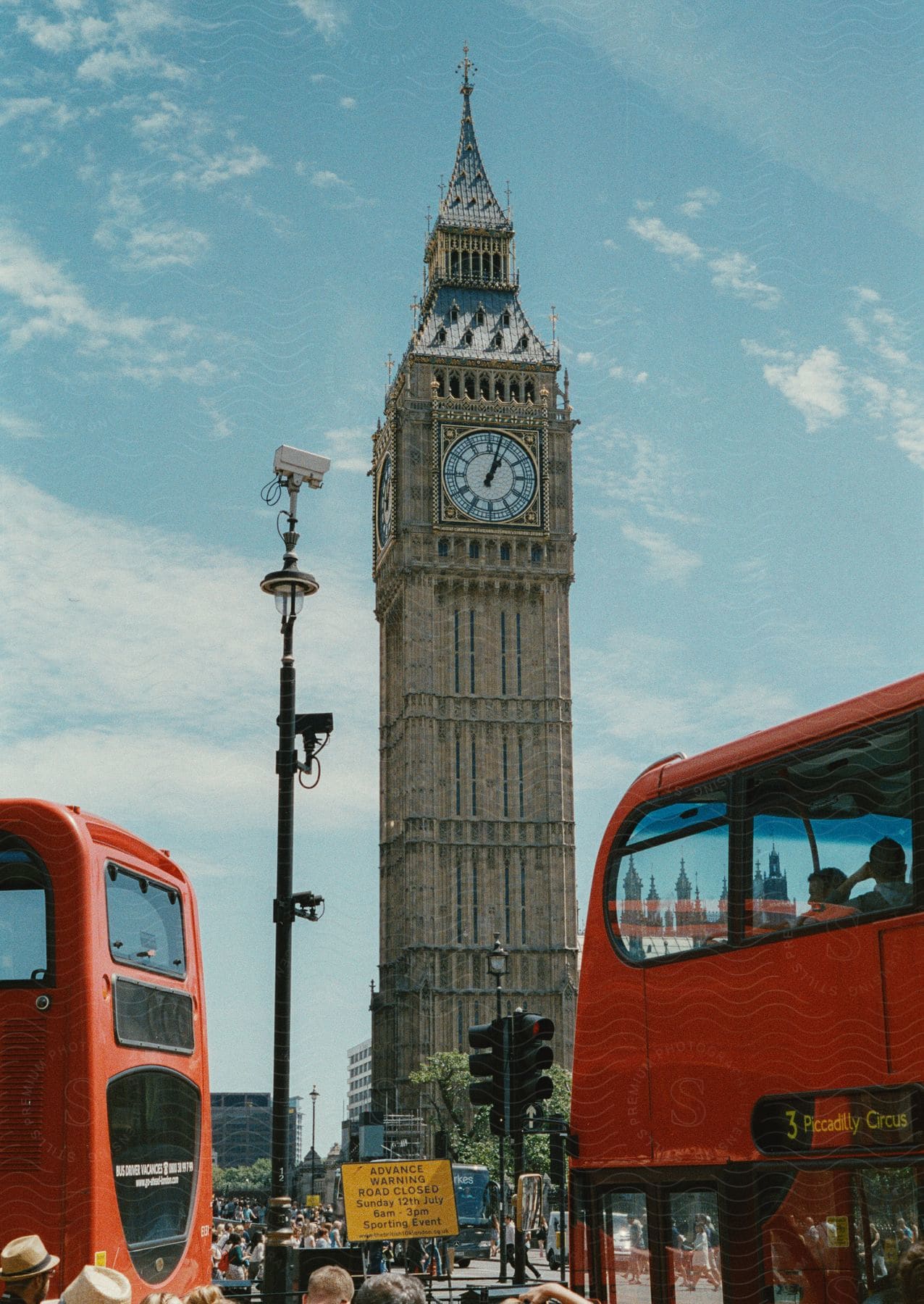 A City Photo Showing A Busy Street With Pedestrians And Red Buses Filled With People