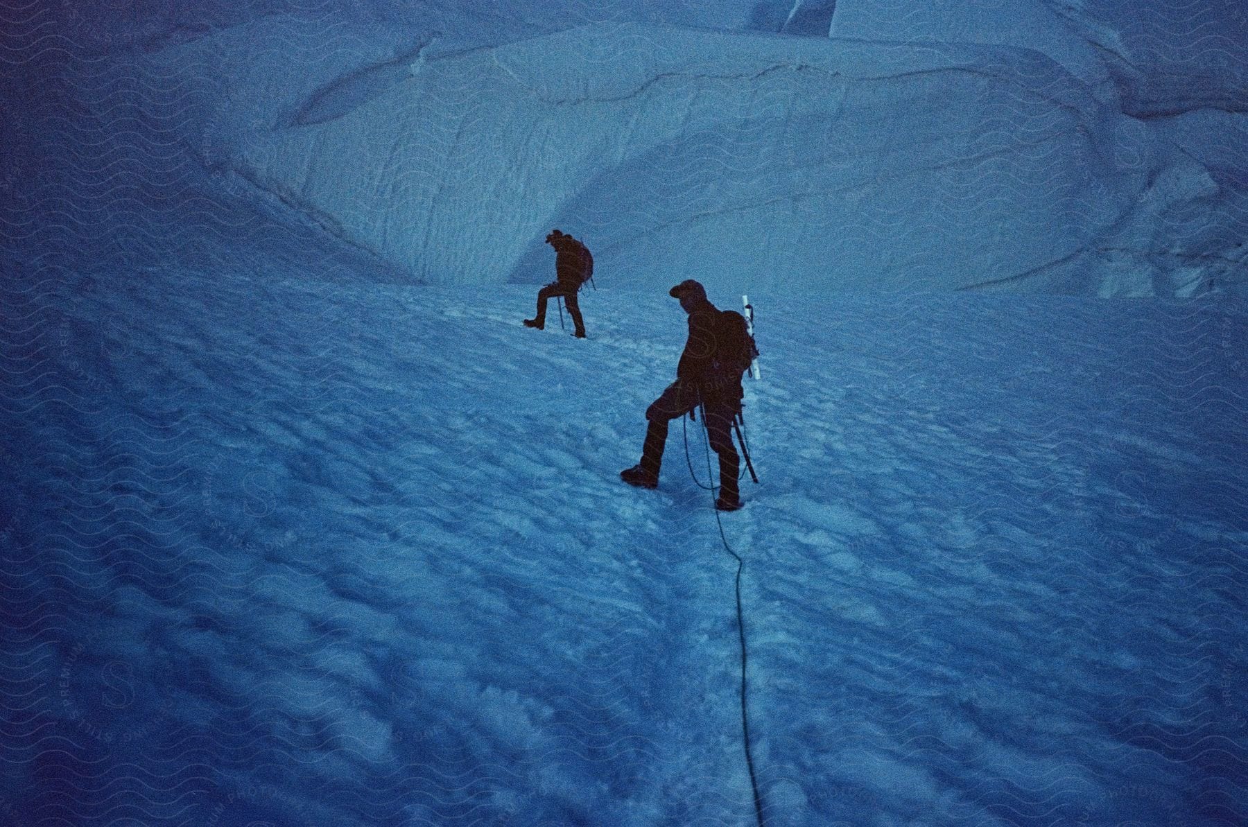 Two adults hiking up a snowcovered mountain