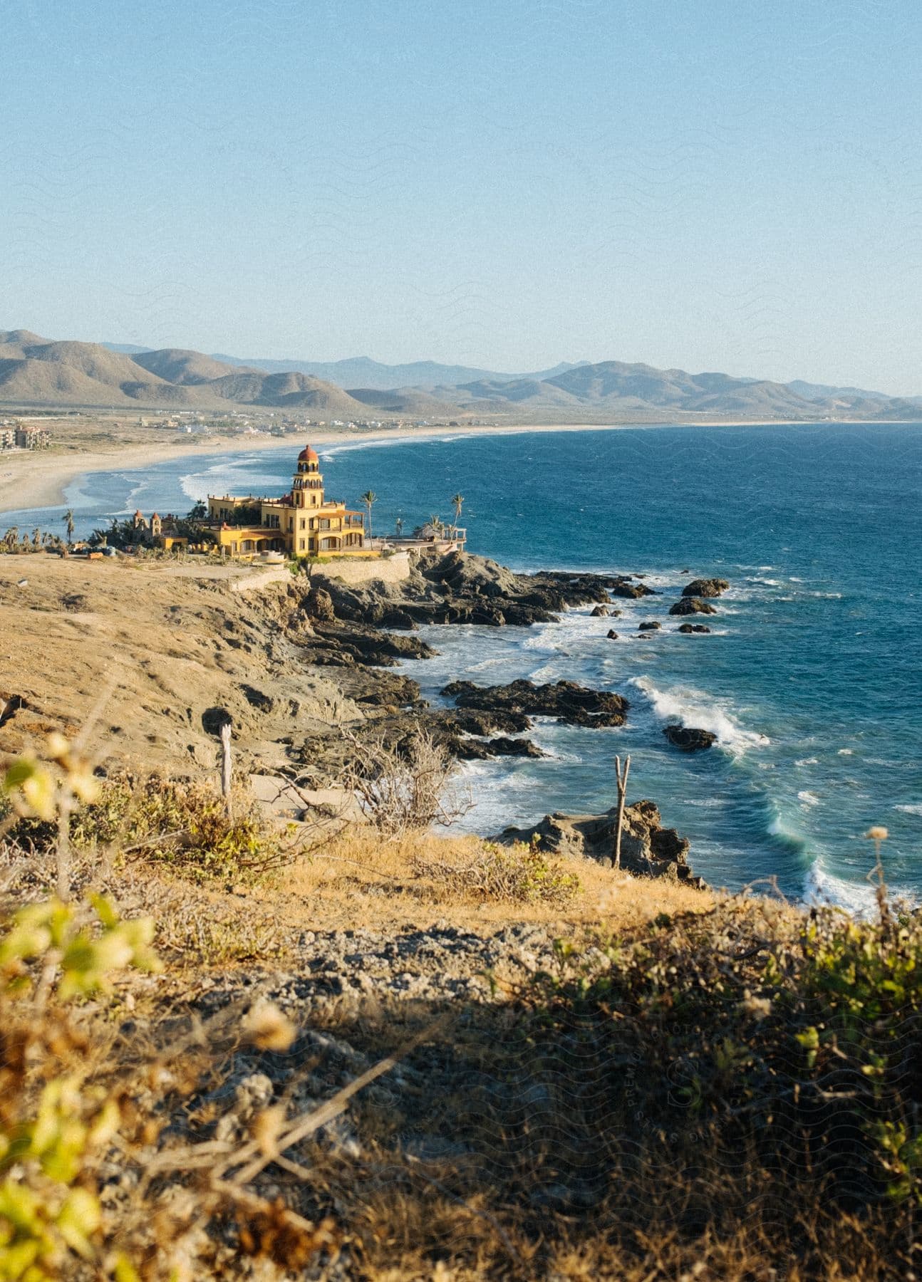 A serene coastal landscape with a rocky shoreline and a clear blue sky