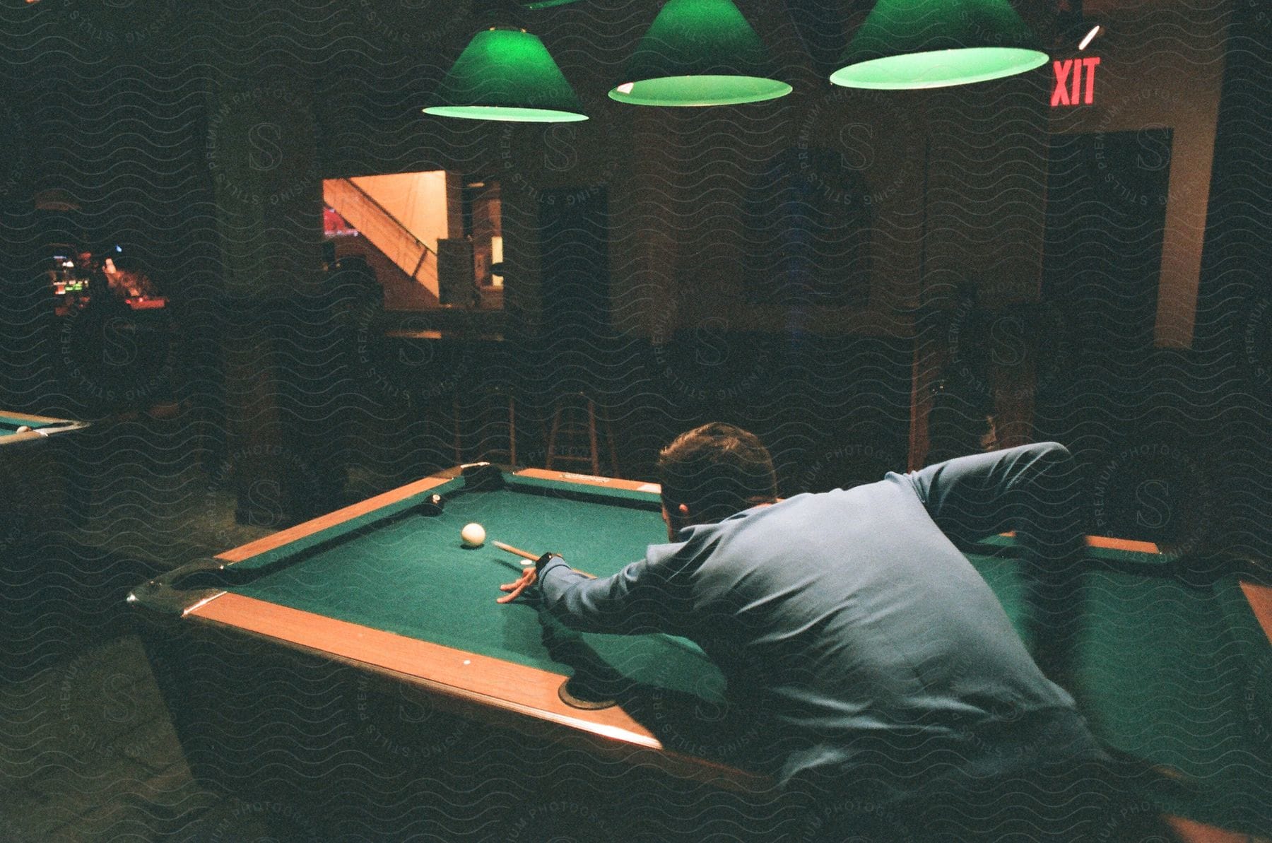 A man playing pool in a bar at night.