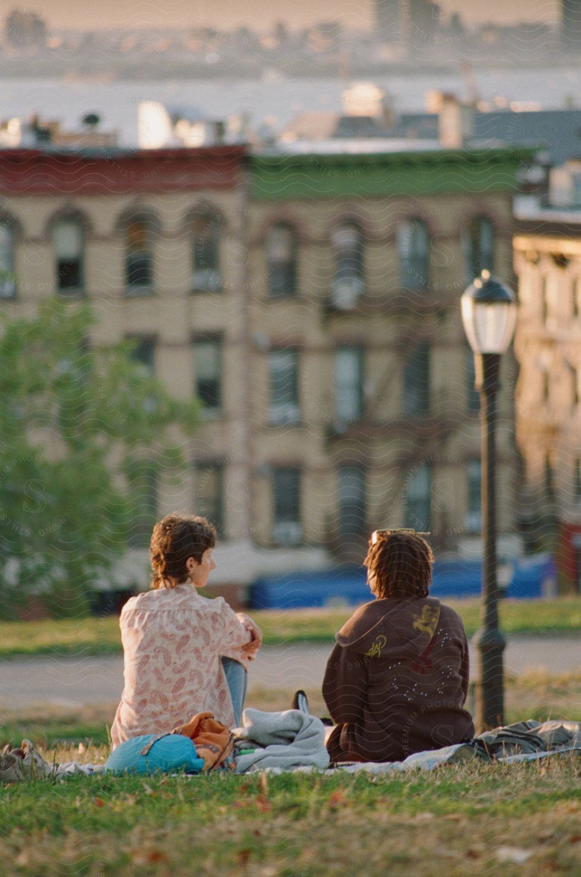 Two women are sitting on a blanket talking.