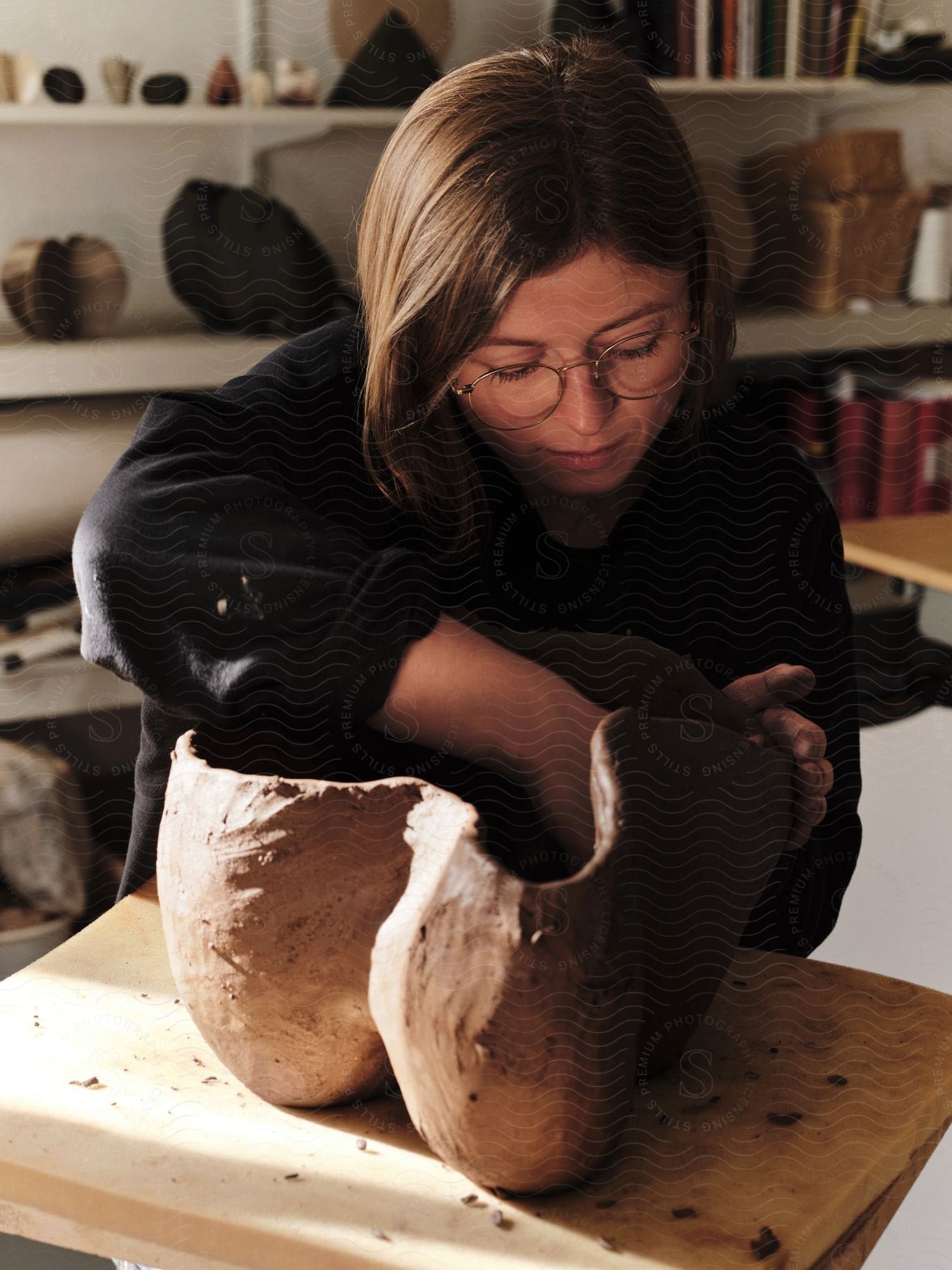 A woman sculpting clay on a workbench in her studio