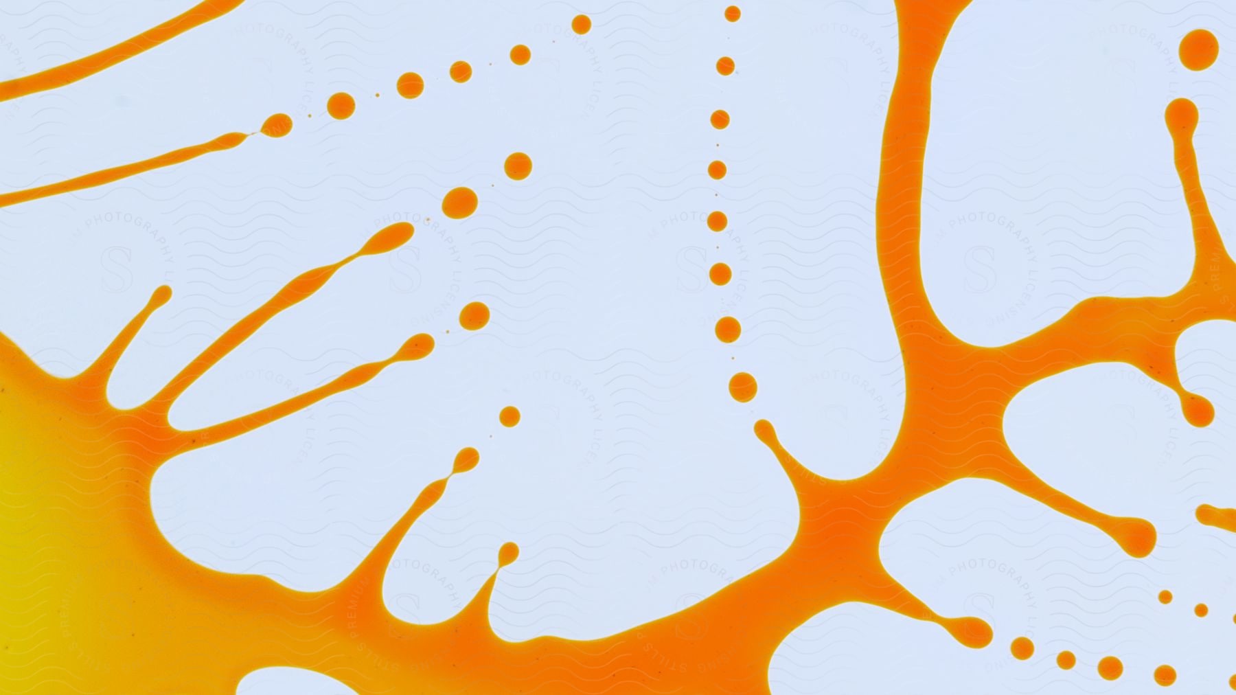 A splash of orange oil liquid on a white surface