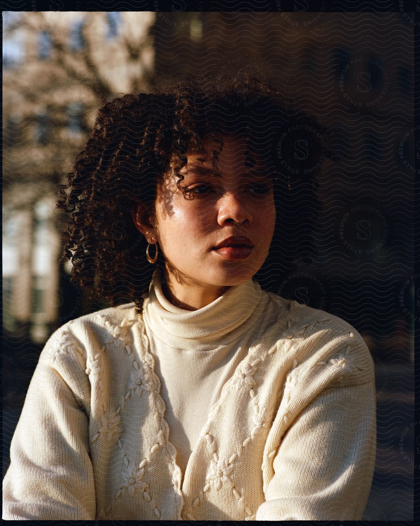 A young woman wearing a white turtleneck and sweater poses for a portrait in downtown manhattan