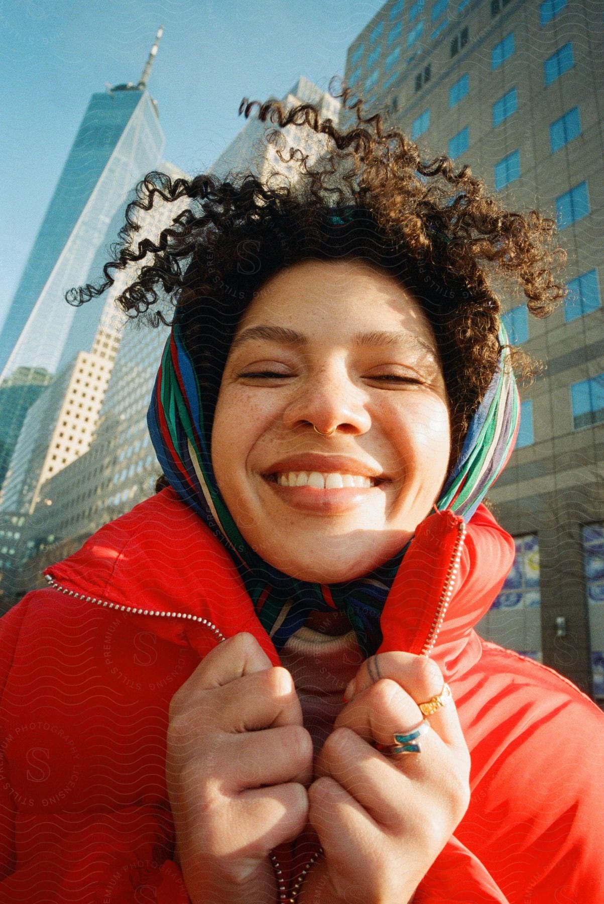 A smiling woman in an orange coat holds onto the top of her coat