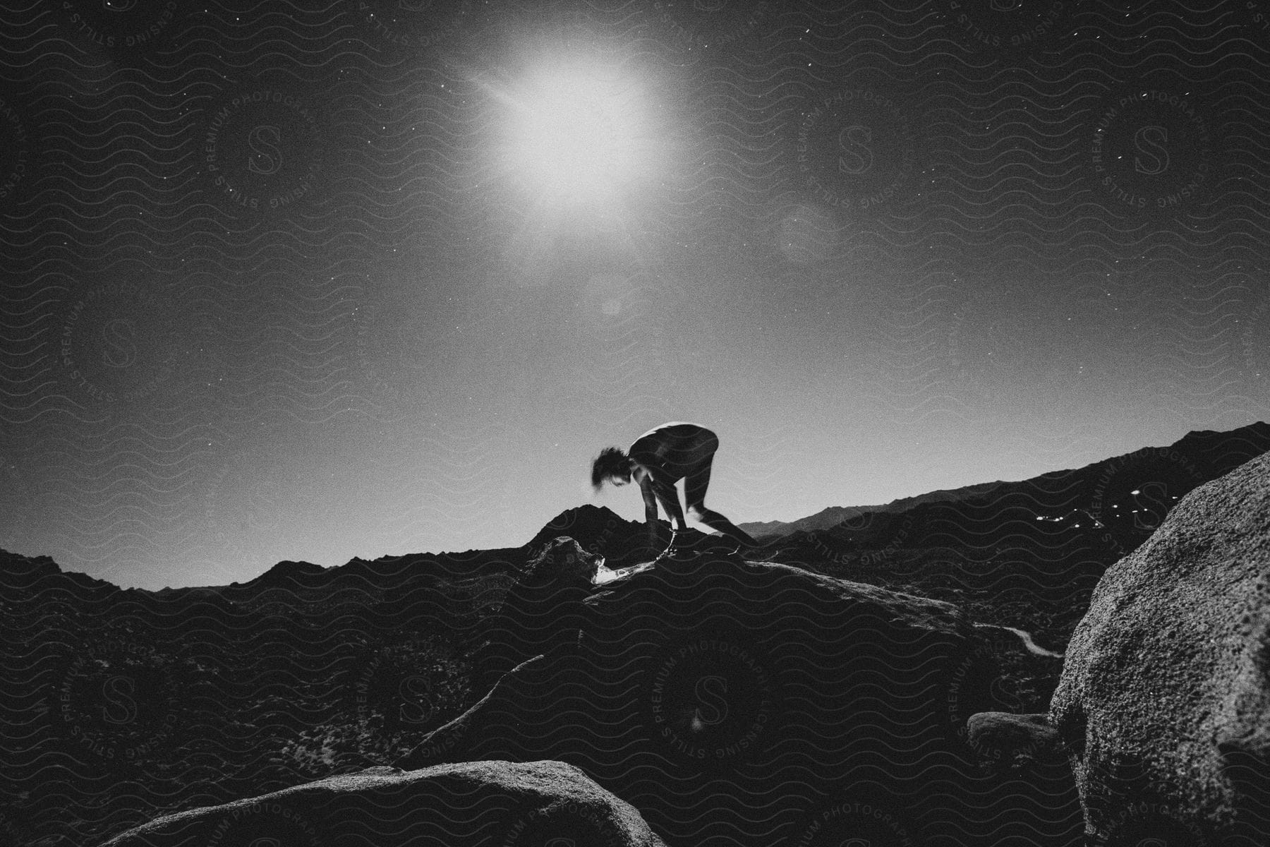 A man in a crouch start position on a large rock in a desert