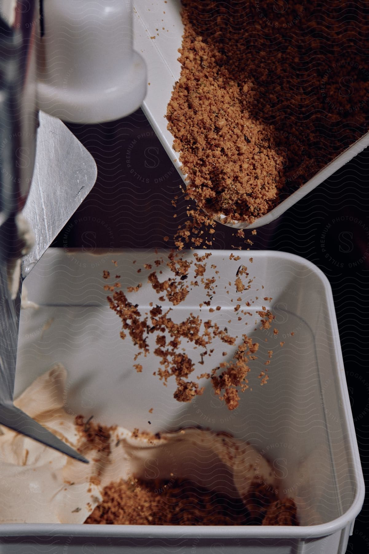 Crumbs being poured over ice cream by a machine for industrial production