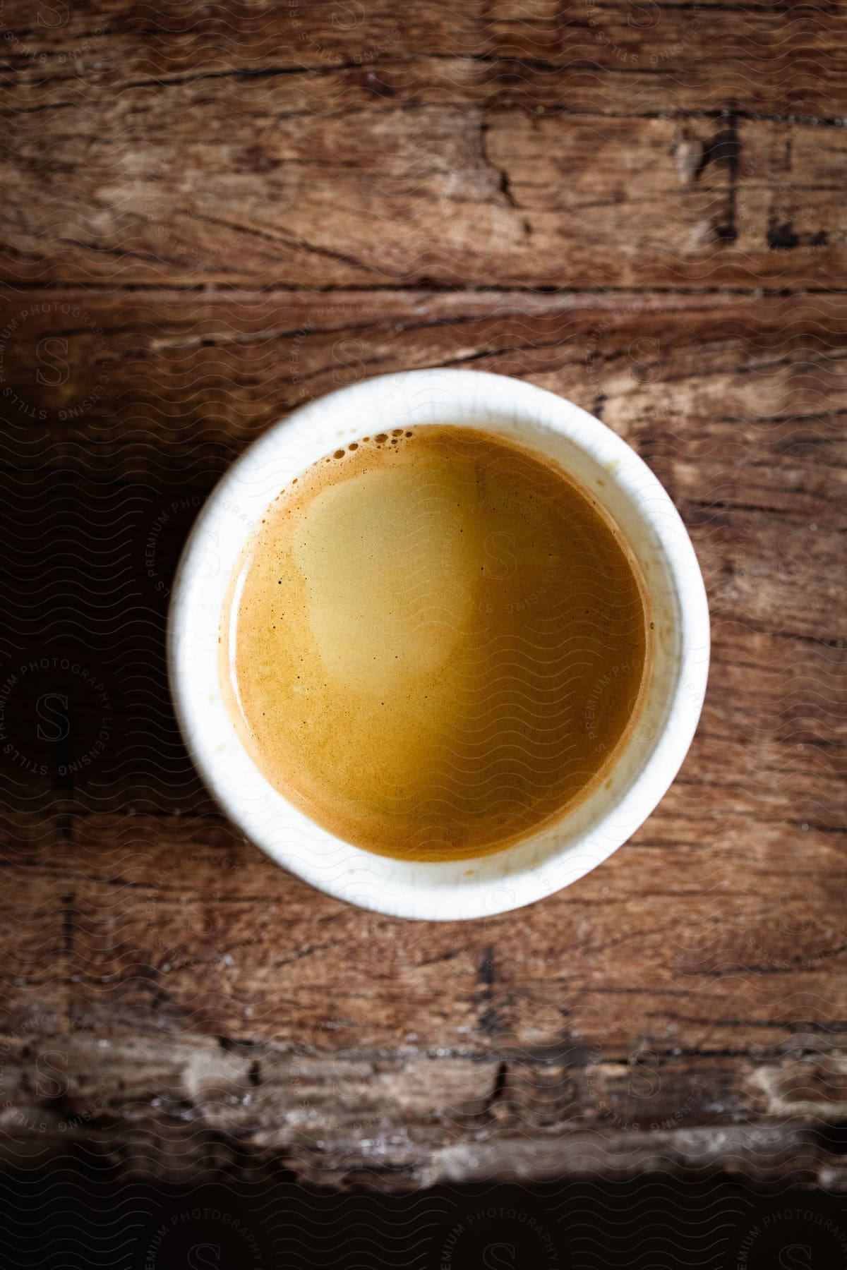 A coffee cup with a creamy coffee beverage in it sitting on a wooden table