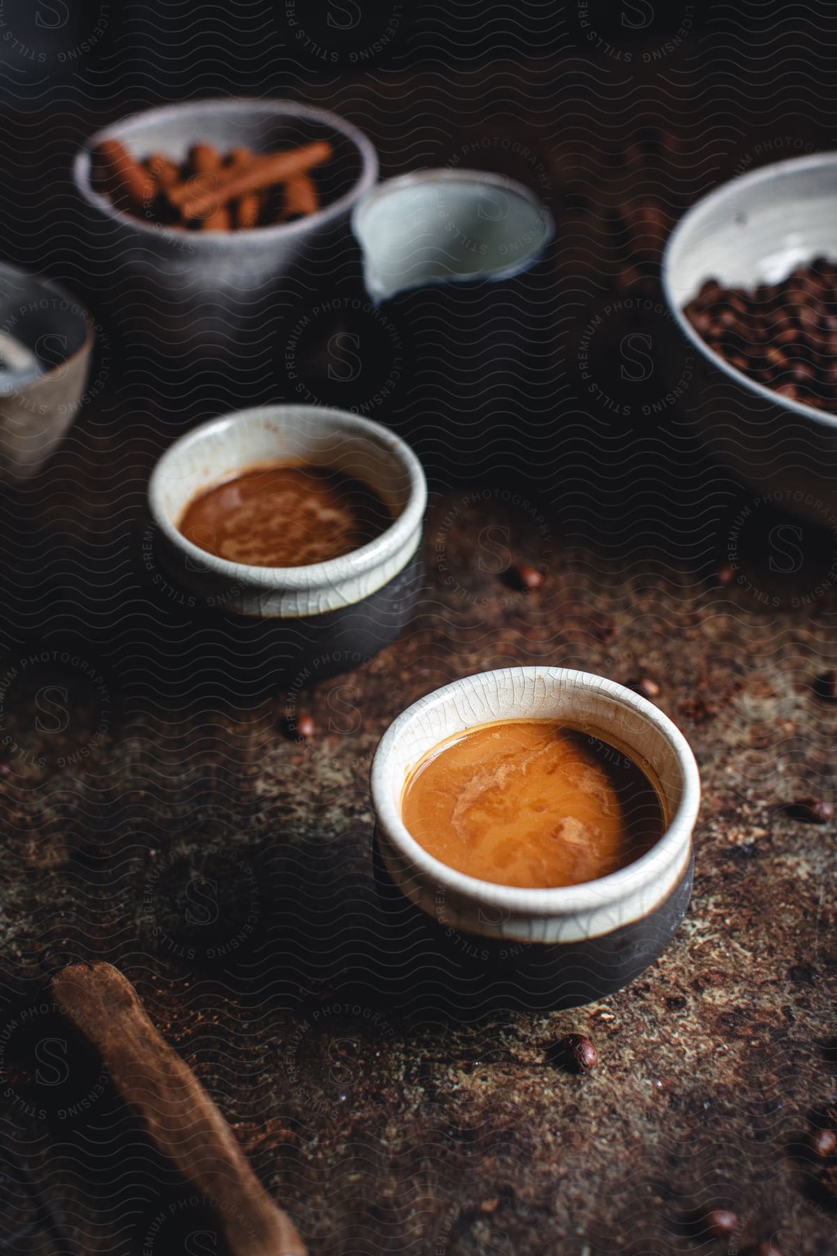 Small black and white ceramic cups of coffee on a table with assorted pottery and food