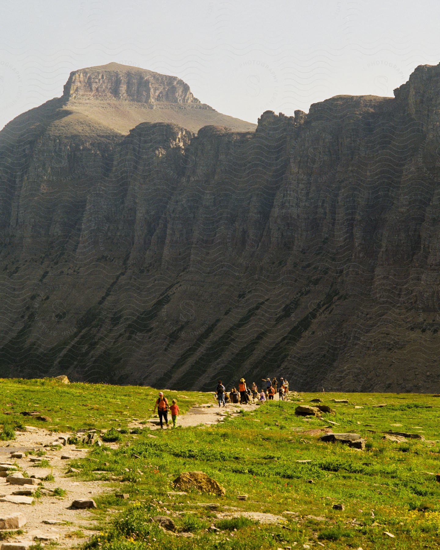 A crowd of people hikes around pollock mountain in glacier national park