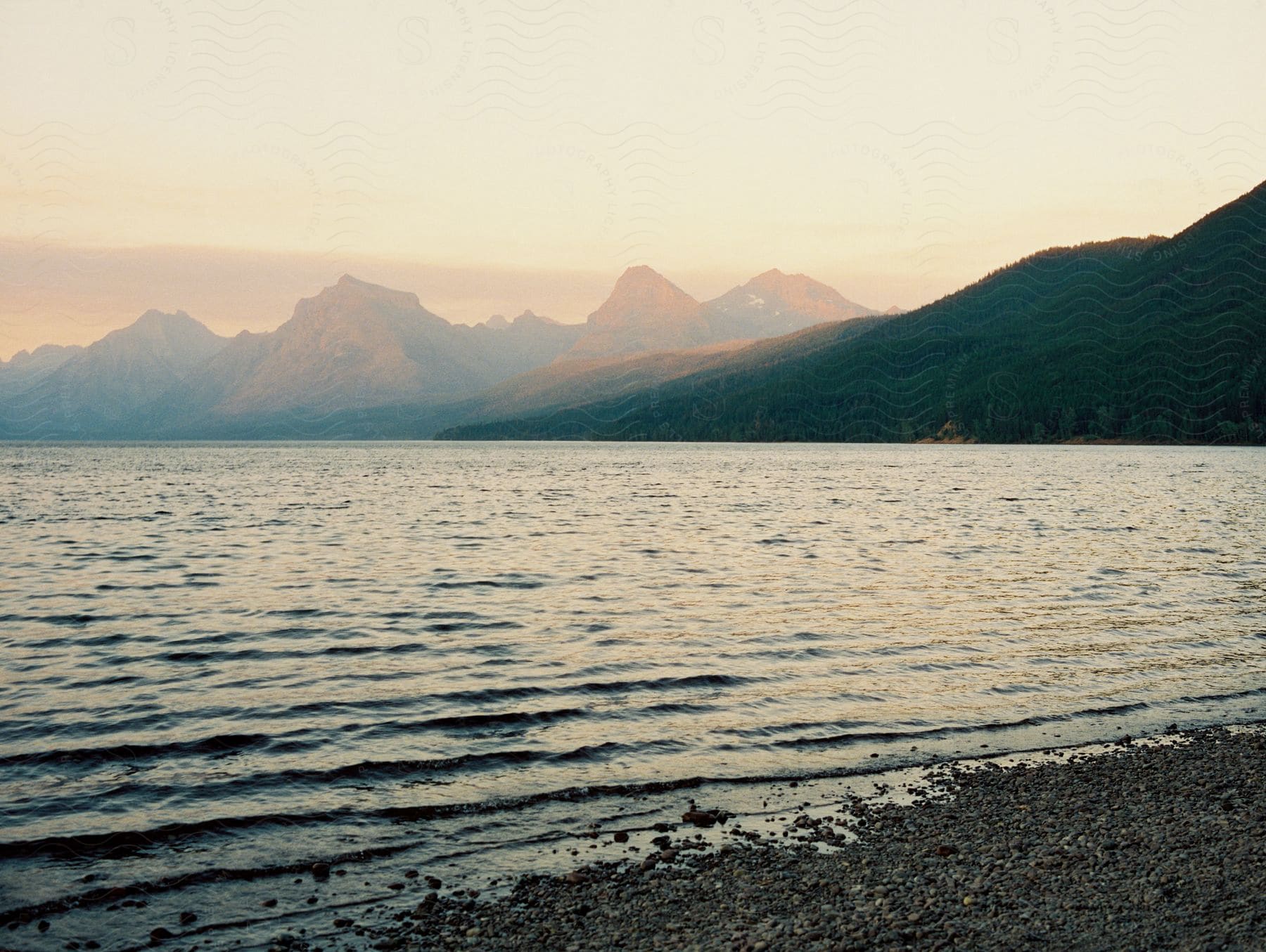 A sunset view of a large lake with mountains in the distance