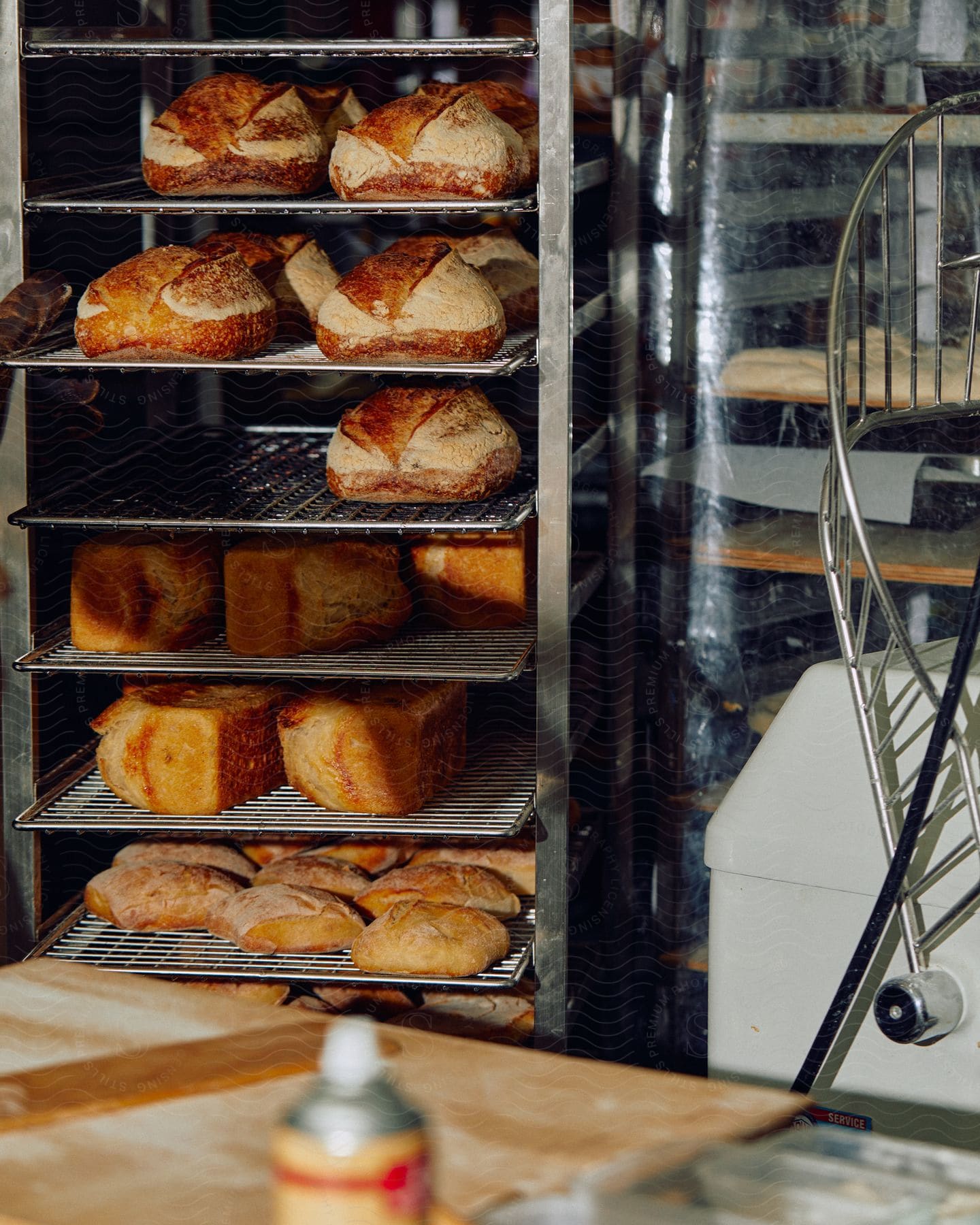 Breeds of several types stored on a metal shelf around breadmaking tools and accessories in an industrial kitchen