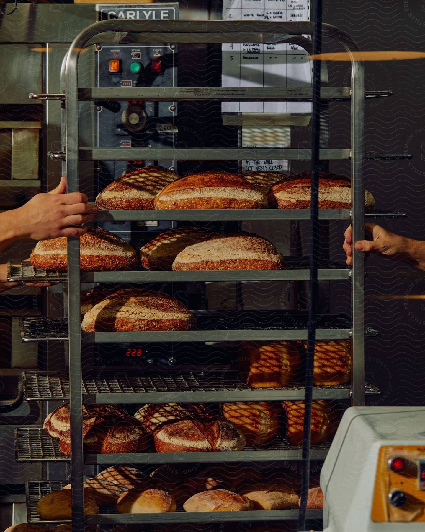 People moving a rack of freshly baked bread in a bakery