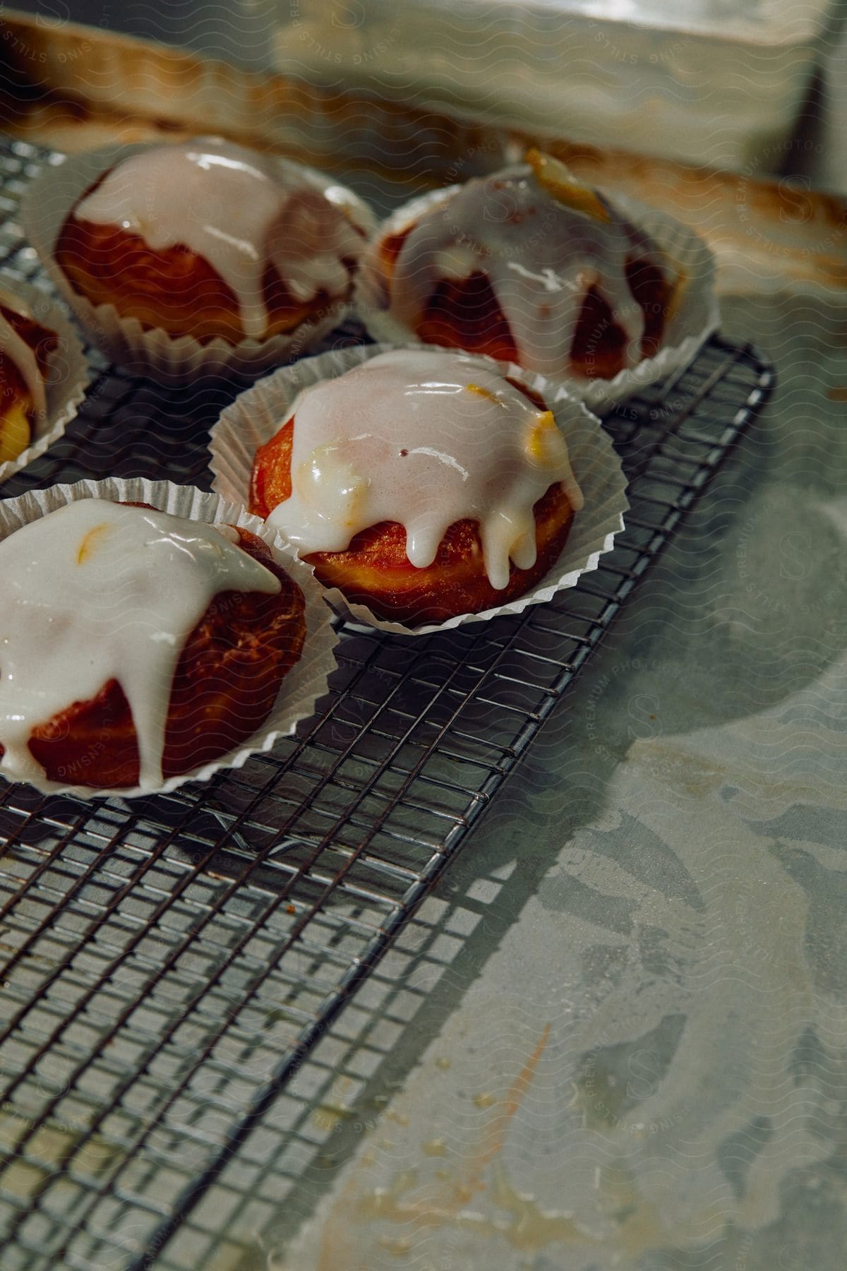 Glazed muffins with orange zest cool on a baking rack in a kitchen