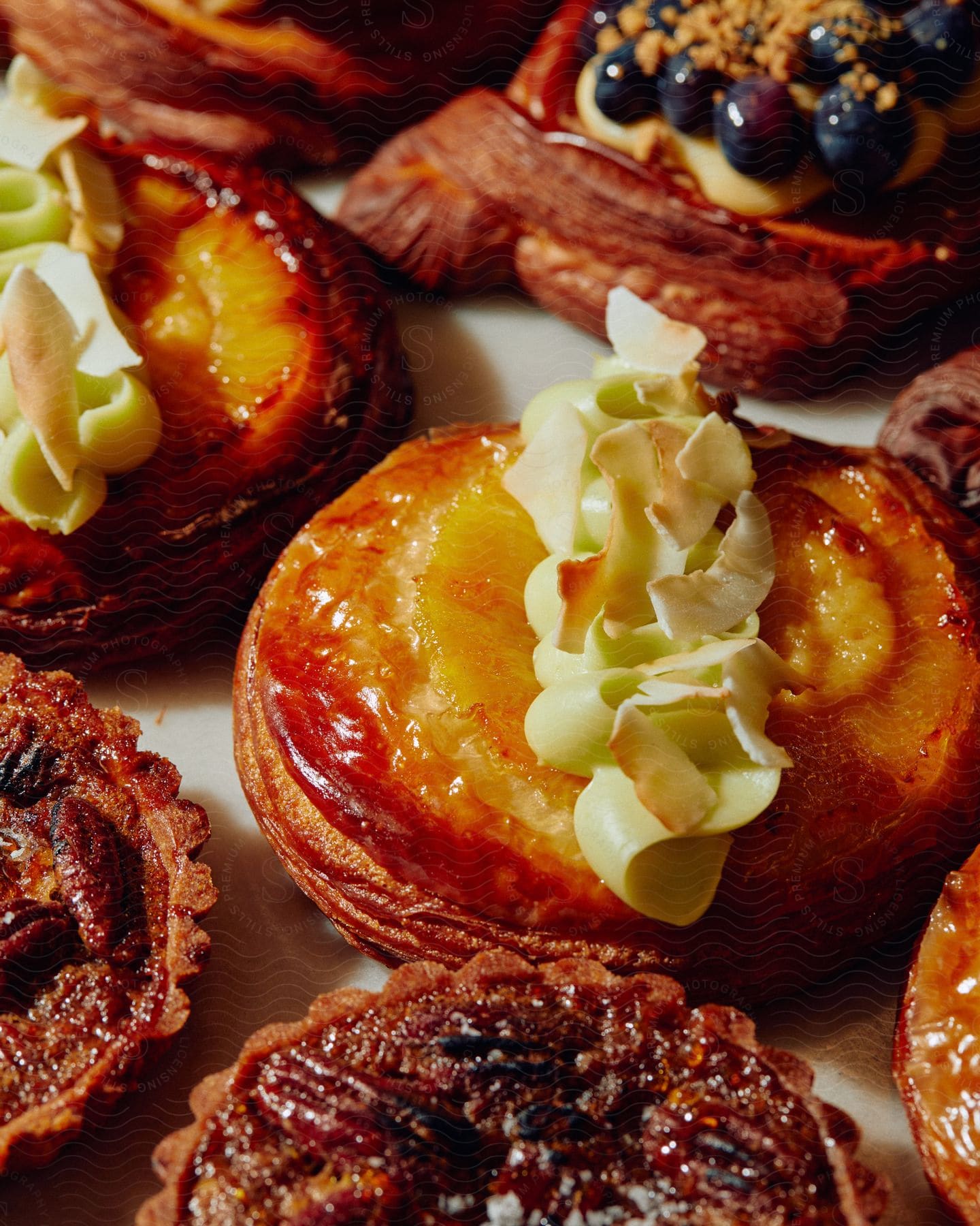 Doughnuts and pastries with fruit and cream are on a table in a commercial kitchen