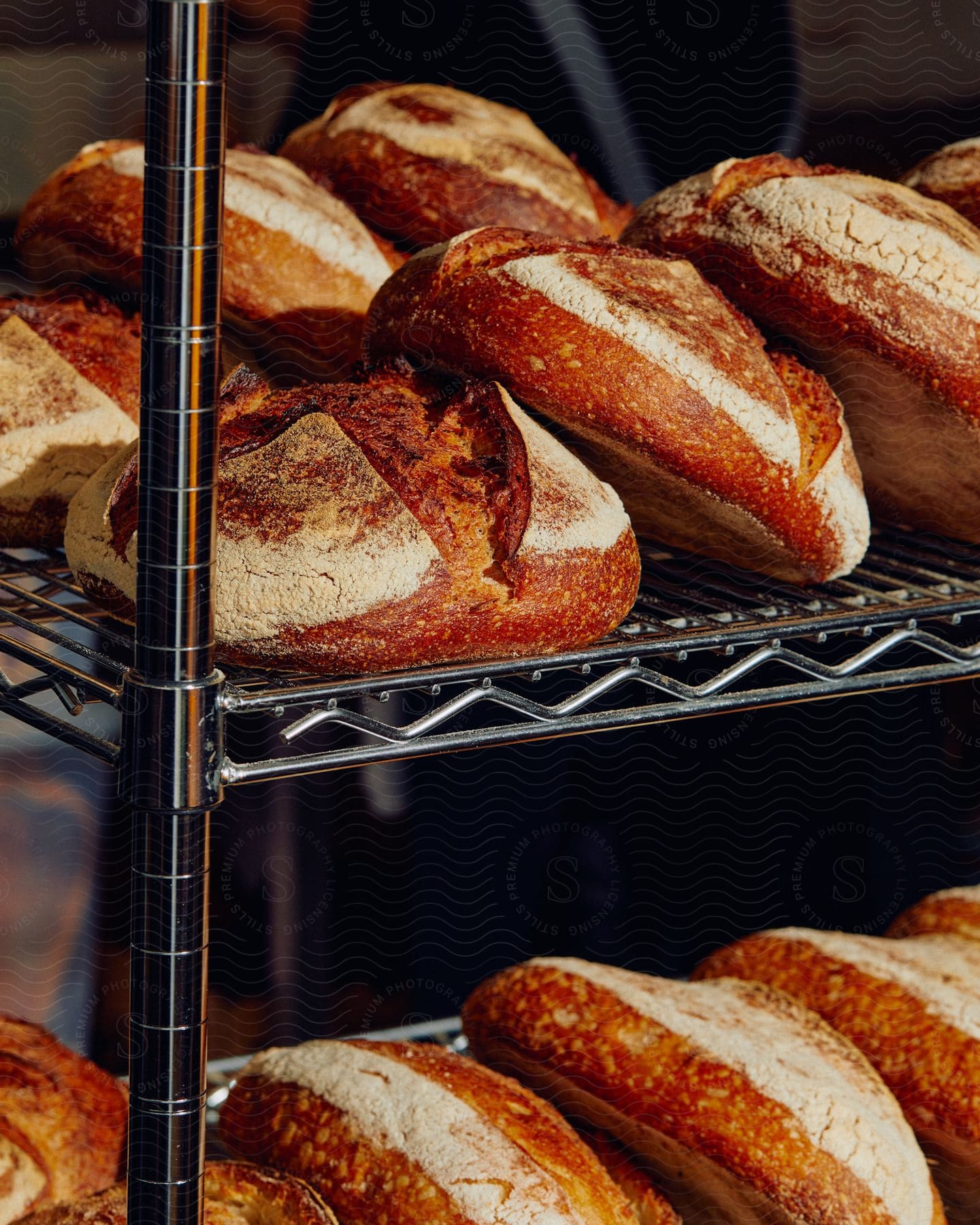 Freshly baked loaves of bread resting on a metallic rack in a commercial kitchen