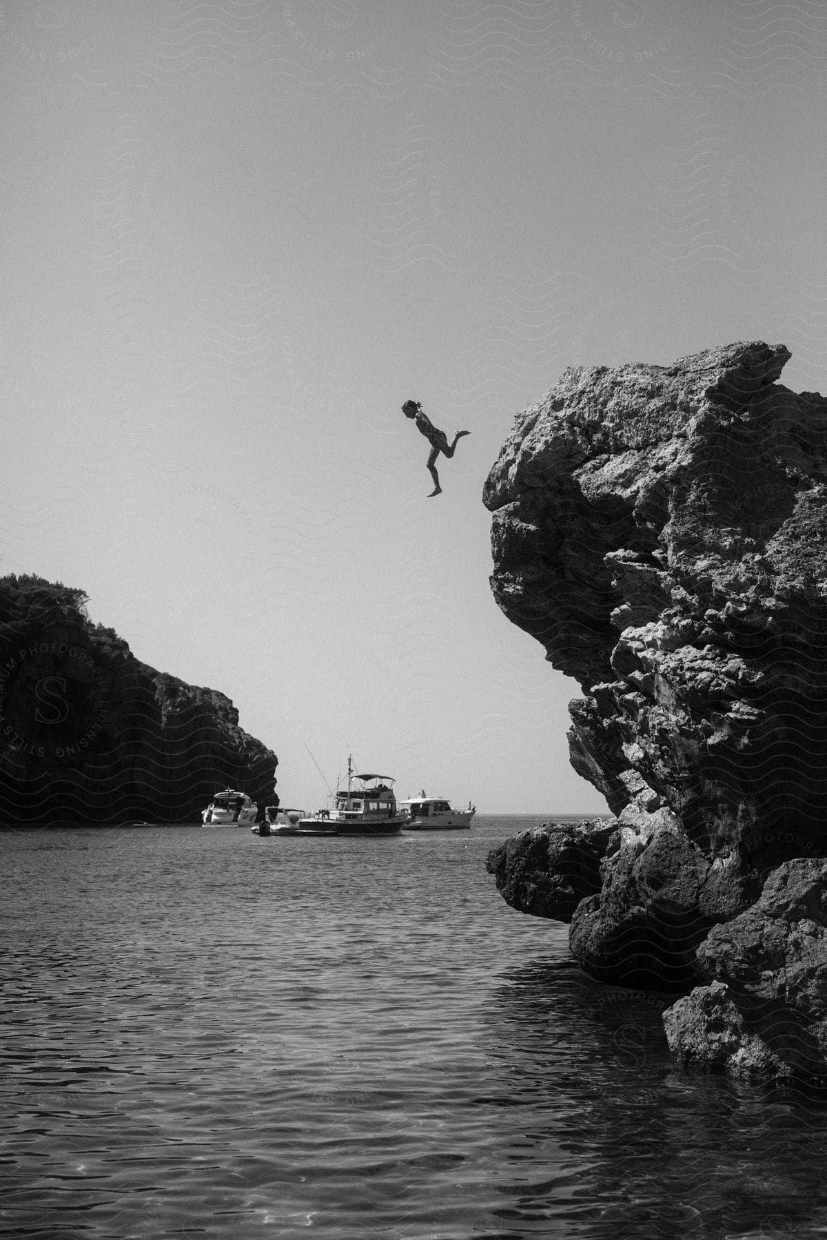 A person jumping from a mountain into an ocean