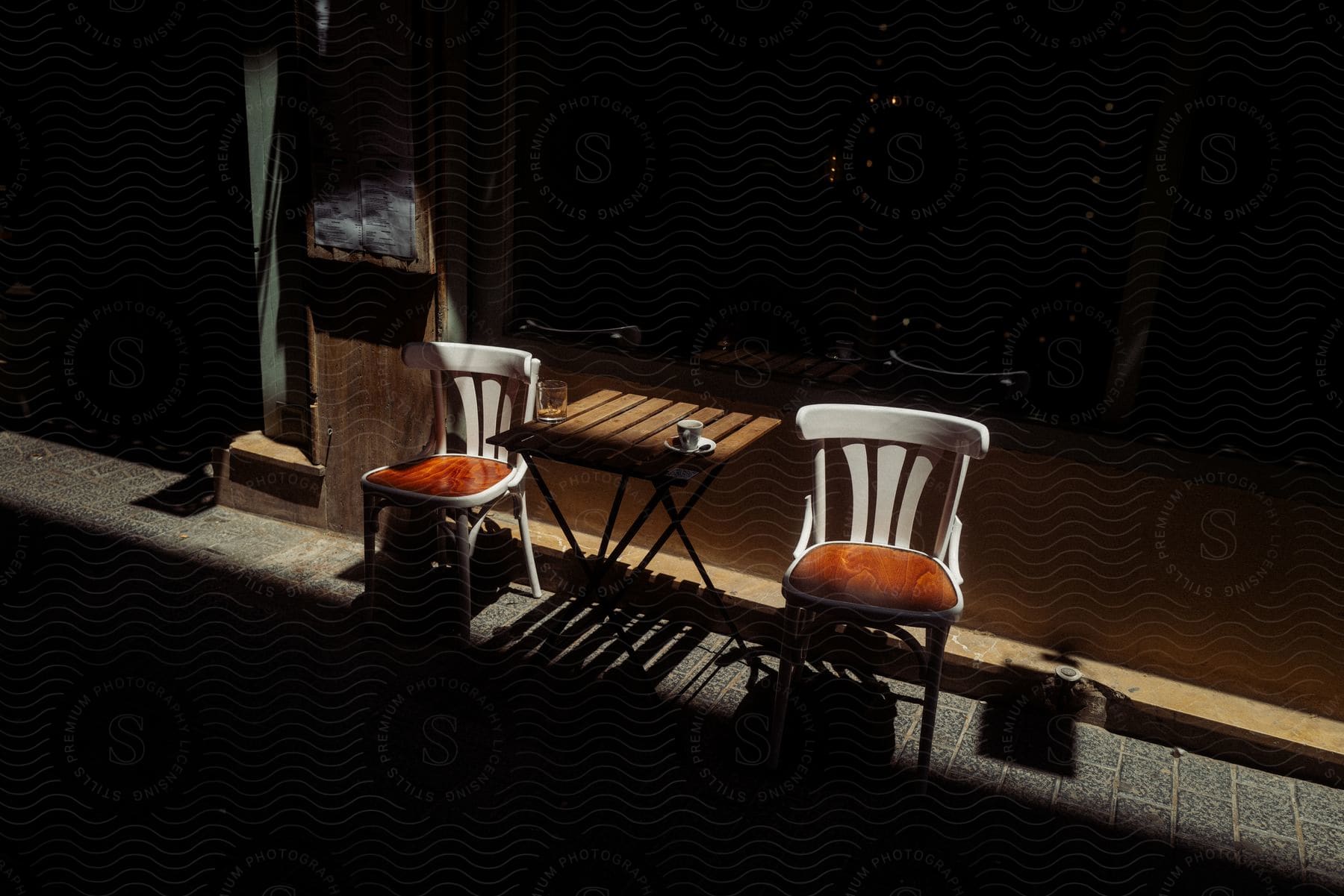 Coffee table two chairs and a coffee mug on the table with a dark evening outside a shop