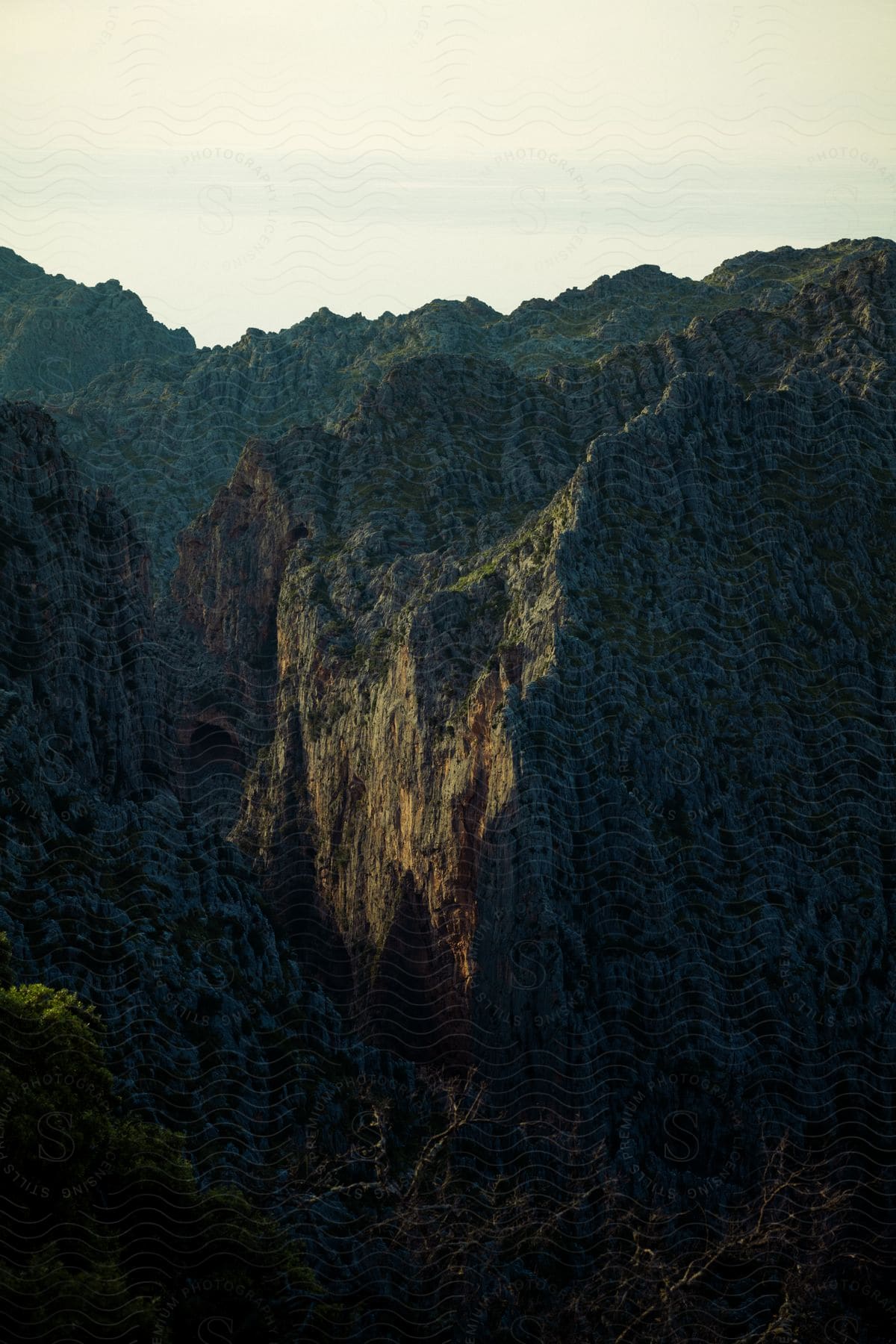 Mountains with a steep cliff and rocky ravine illuminated by sunlight