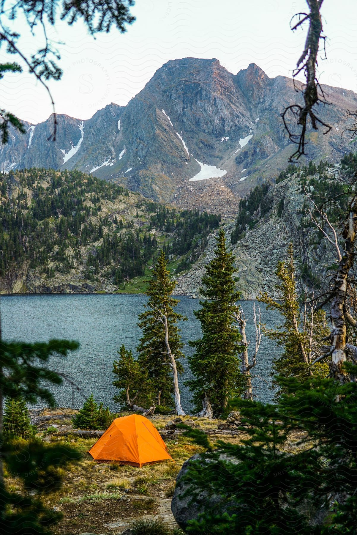 Camping tent by lakeside with mountains in background