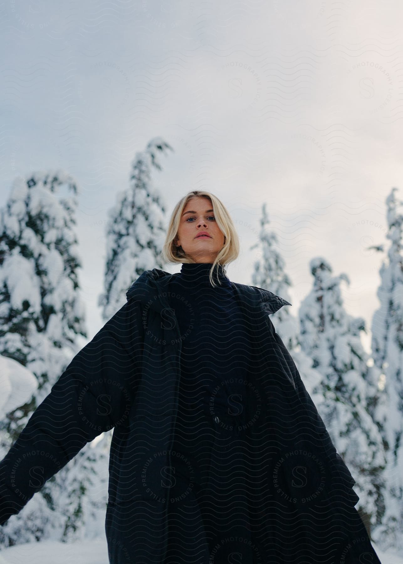 A woman wearing a coat stands outdoors during winter