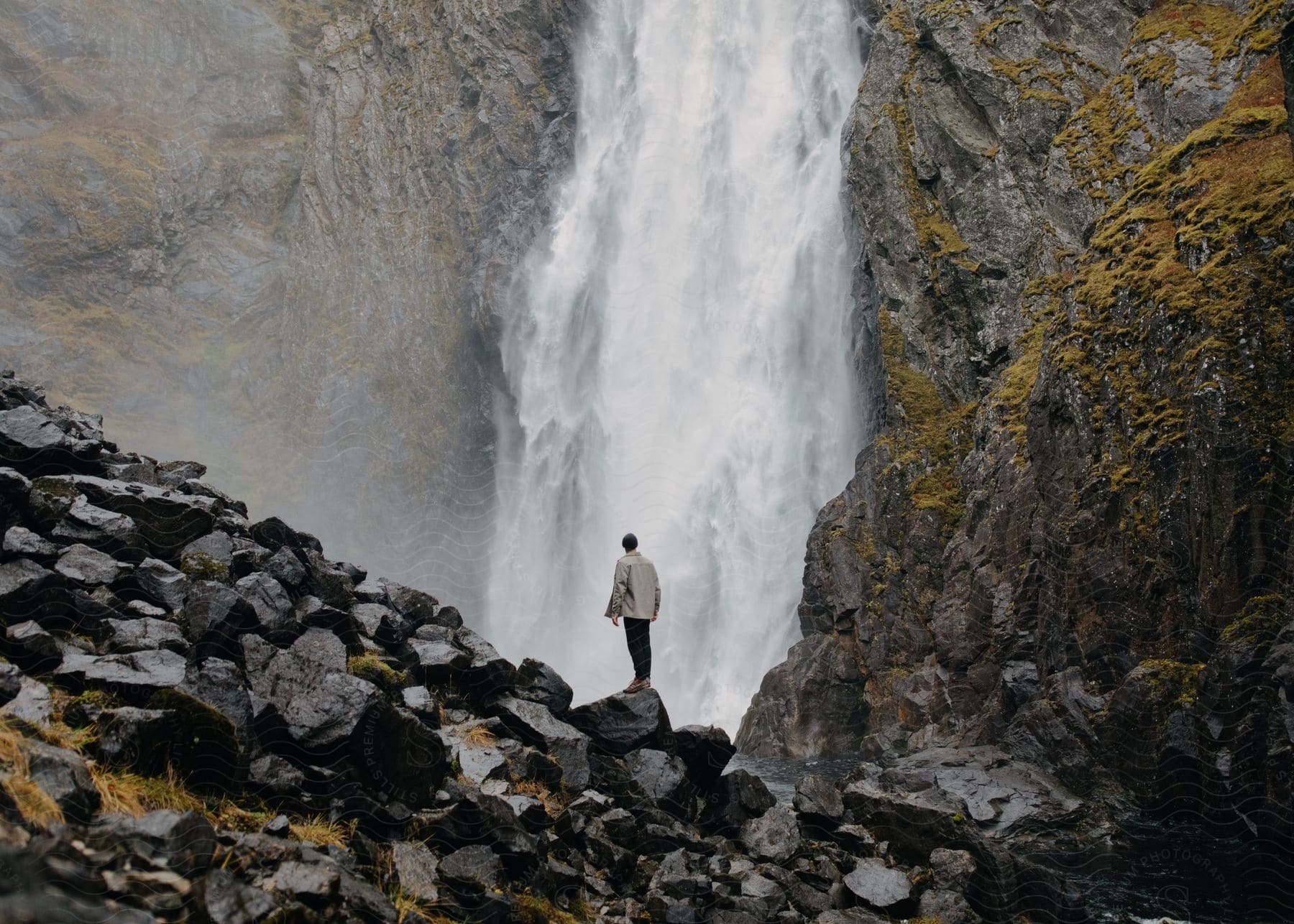 A man sitting on a rock near a waterfall in nature during the day