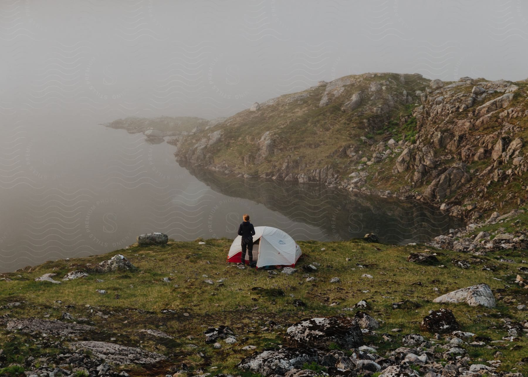 A person in nature near a lake and mountains