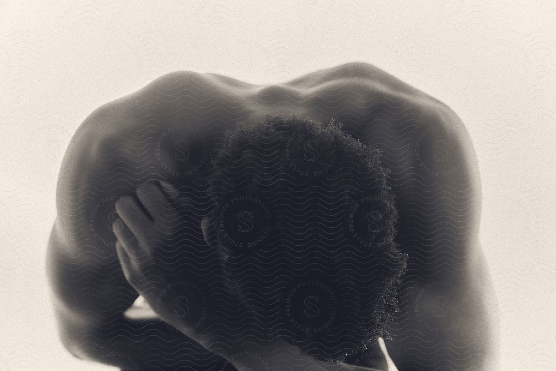 A Shirtless Man Bending Over With The Crown Of His Head Toward The Camera