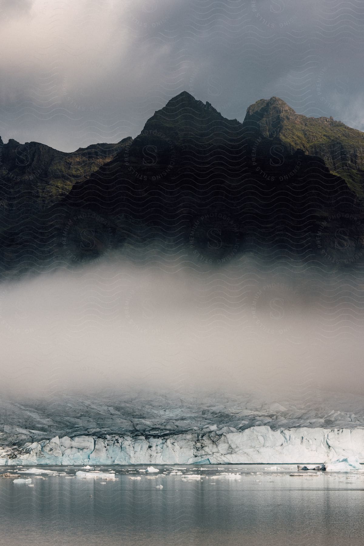 A serene landscape of a lake surrounded by mountains and trees with a cloudy sky overhead