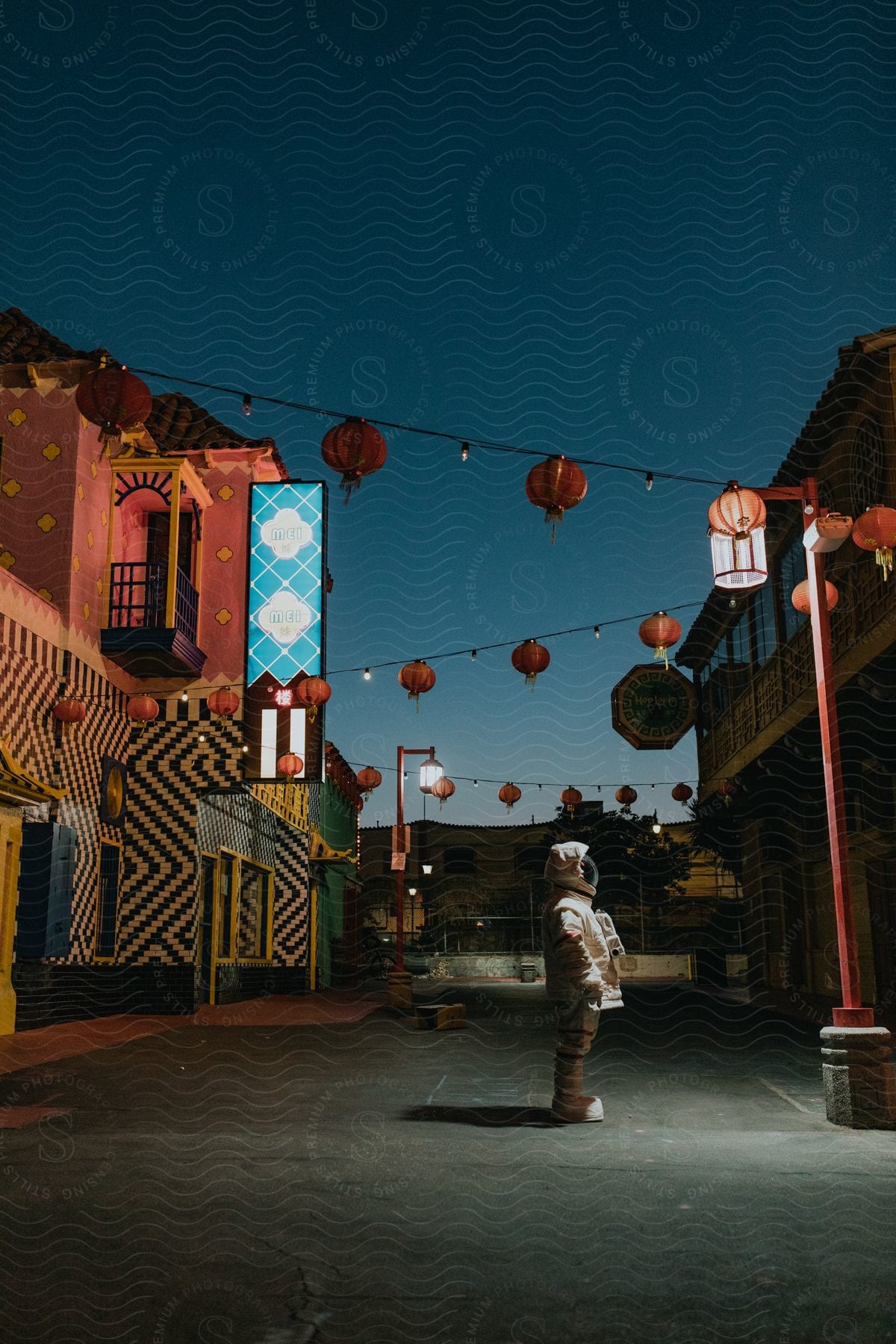 An astronaut in a space suit stands in front of stores on a street at dusk