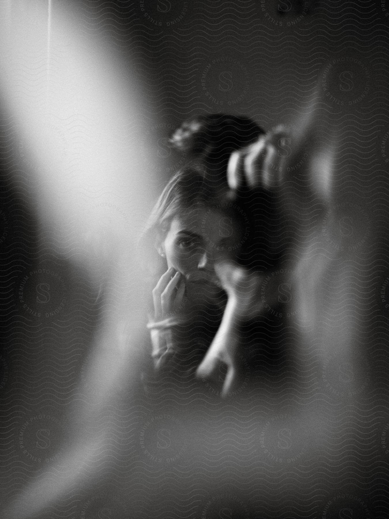 A woman in black and white facing the shot with abstract blurry lights around her in a double exposure