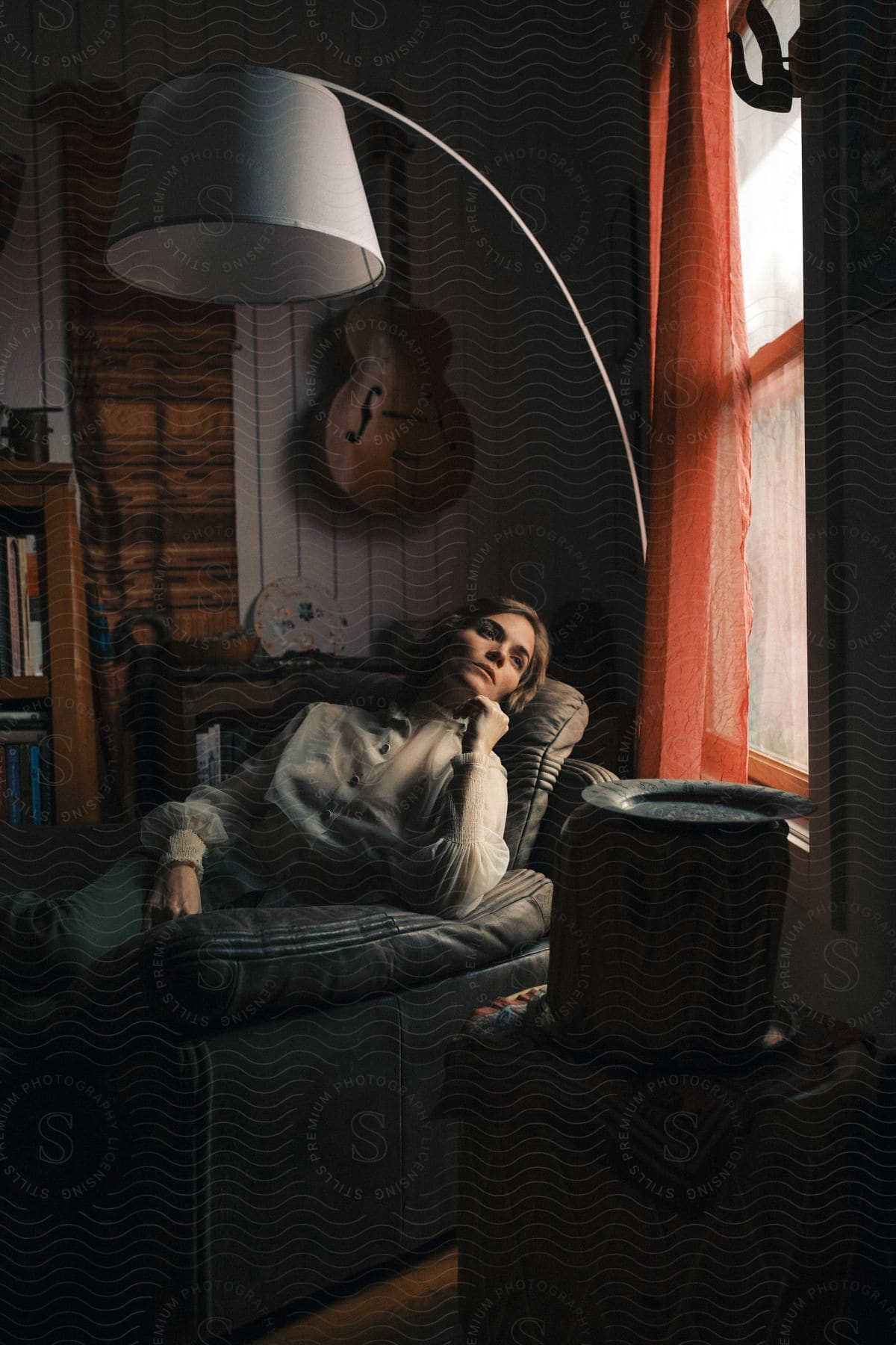 A woman sitting in a lounge chair in her living room with a lamp over her