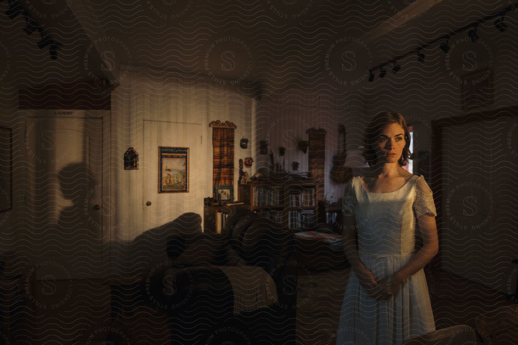 A young woman wearing a white dress standing in her living room