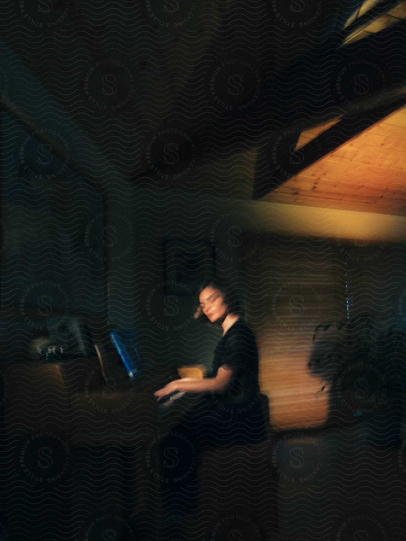 A woman sitting at a piano with her fingers on the keyboard captured in a blurred image