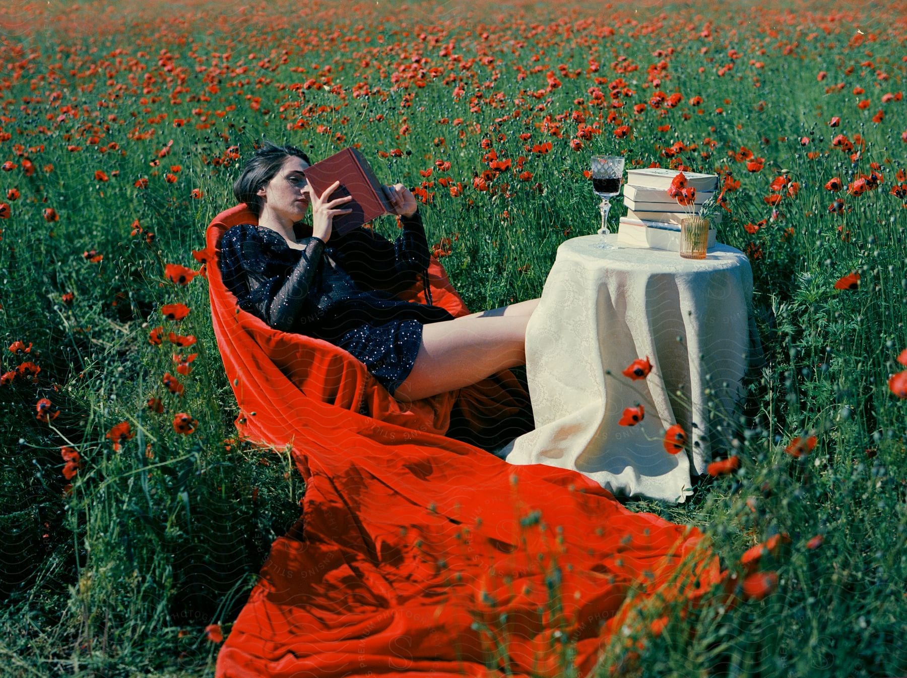 Stock photo of a woman in a formal dress stands alone in a poppy field