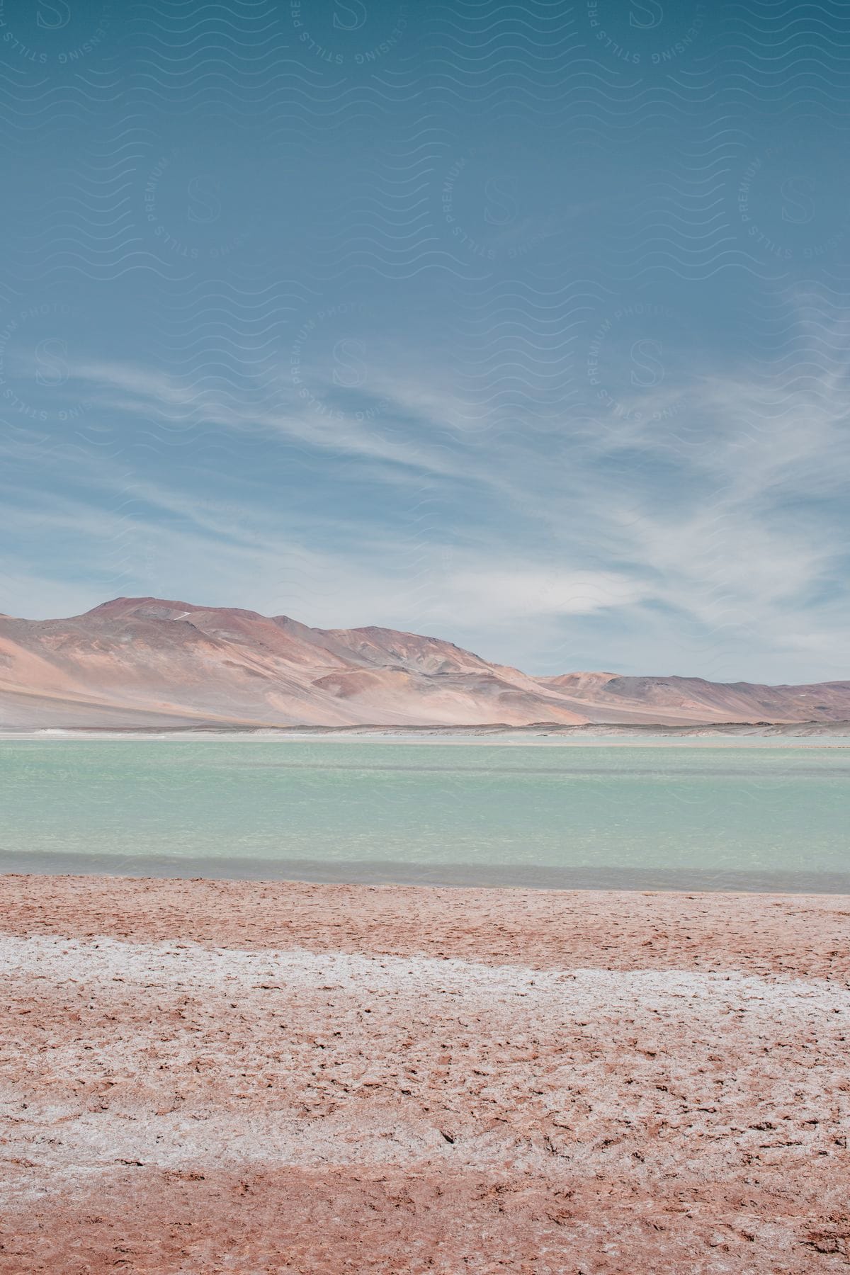 A landscape shot of a gravel beach with the sea and hills in the background