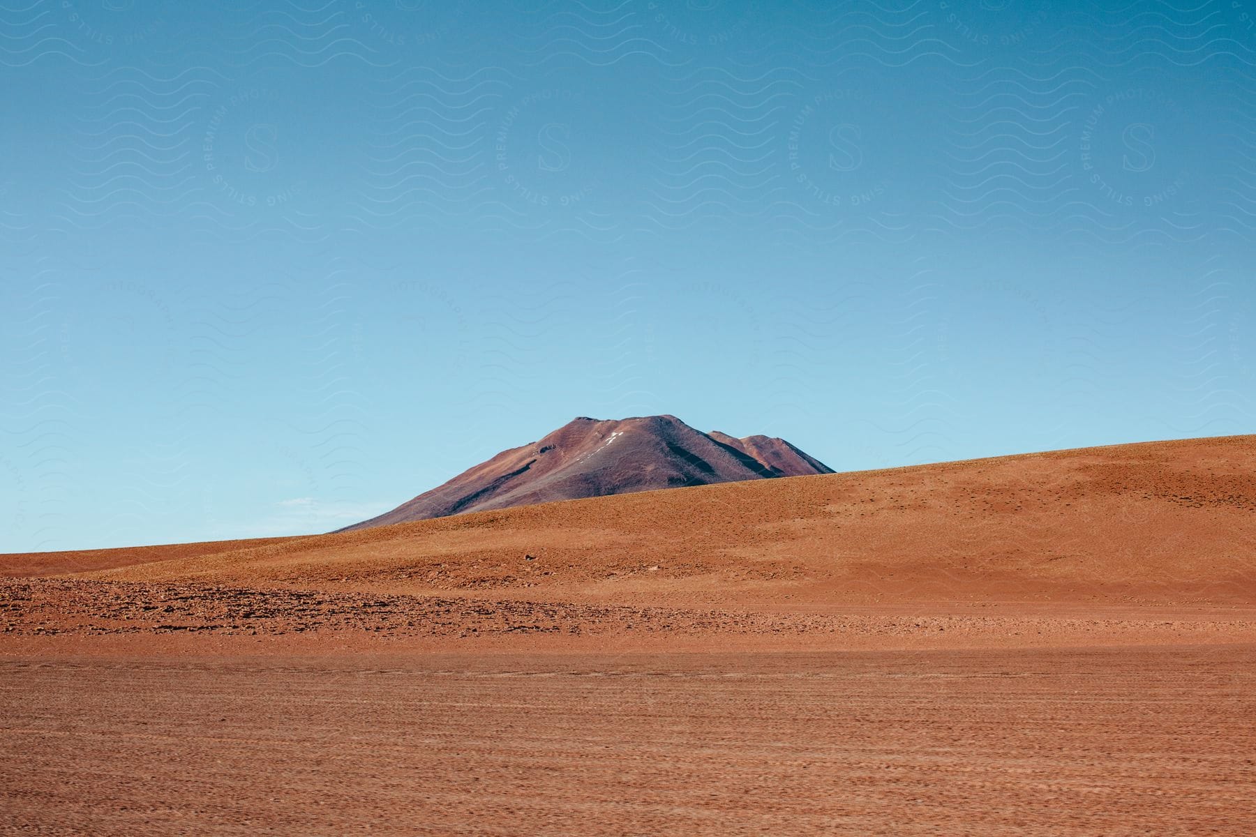 A sandy desert land with a mountain peak in the distance