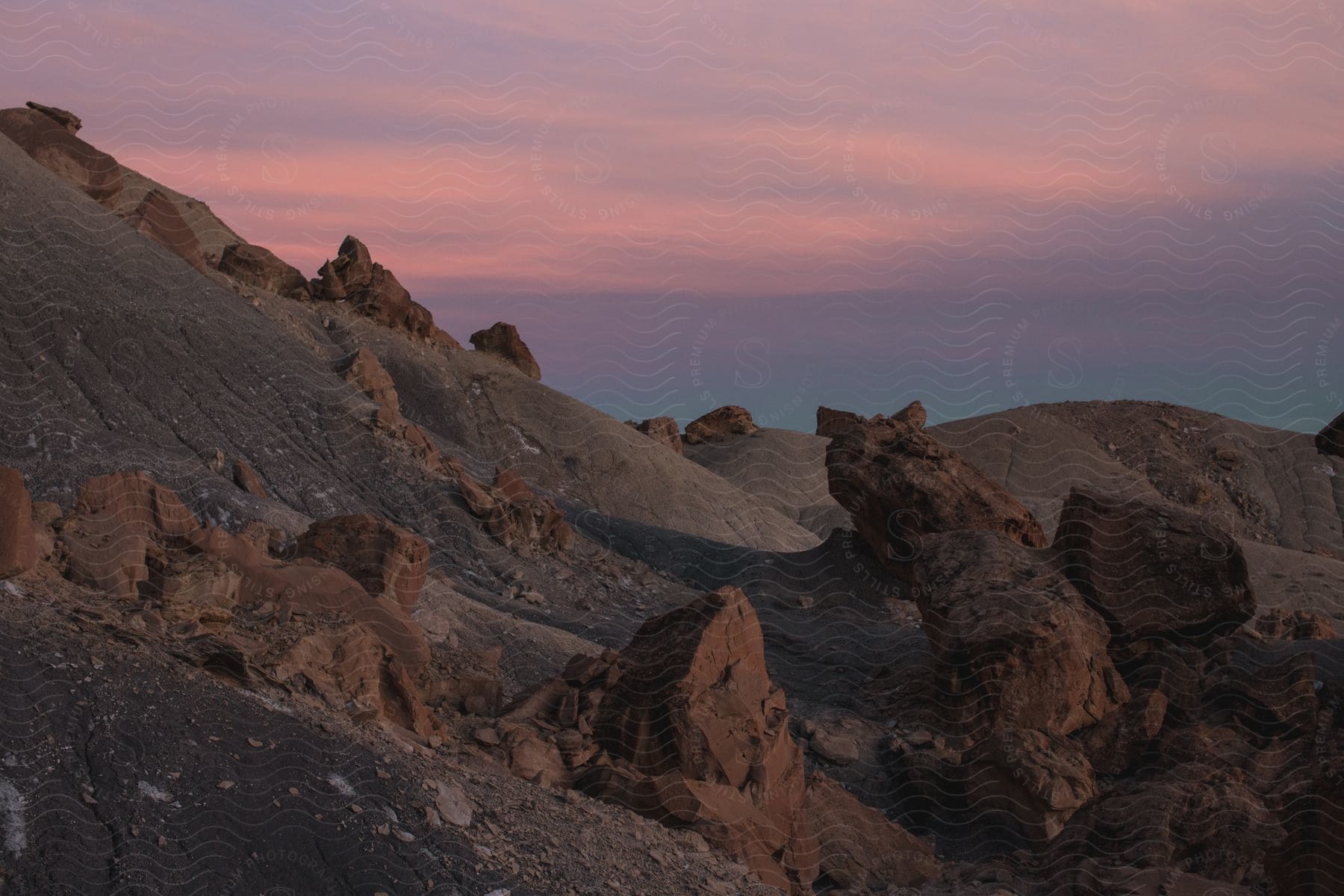 Rocky terrain with large and small boulders against a pink sky