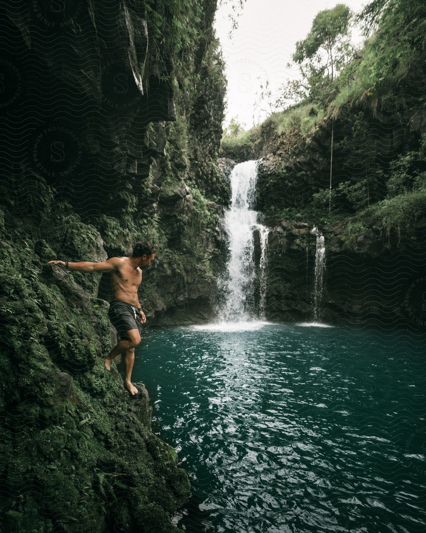 A man standing in a forest with a waterfall