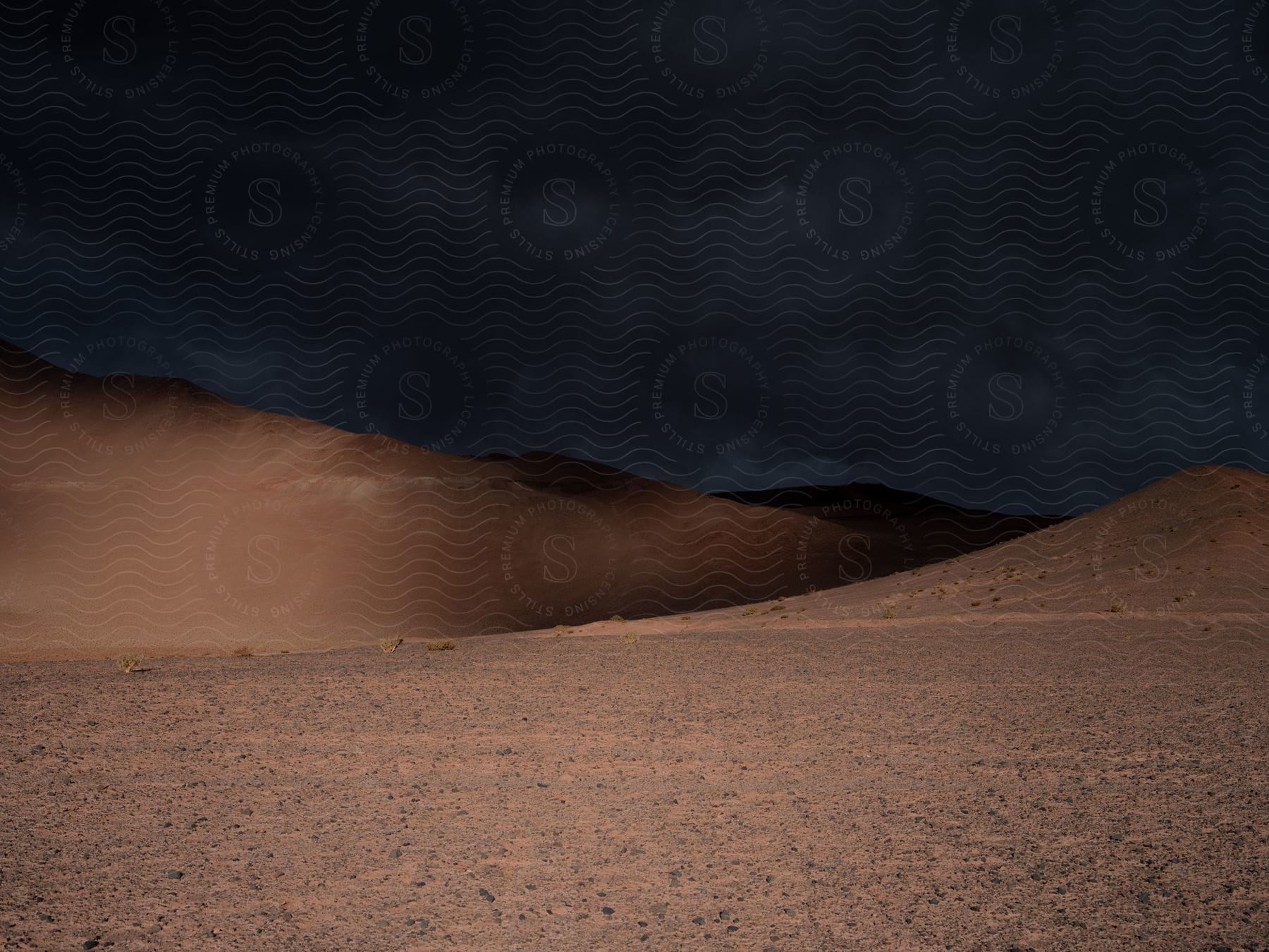 A brewing storm looms above golden sand dunes in the desert